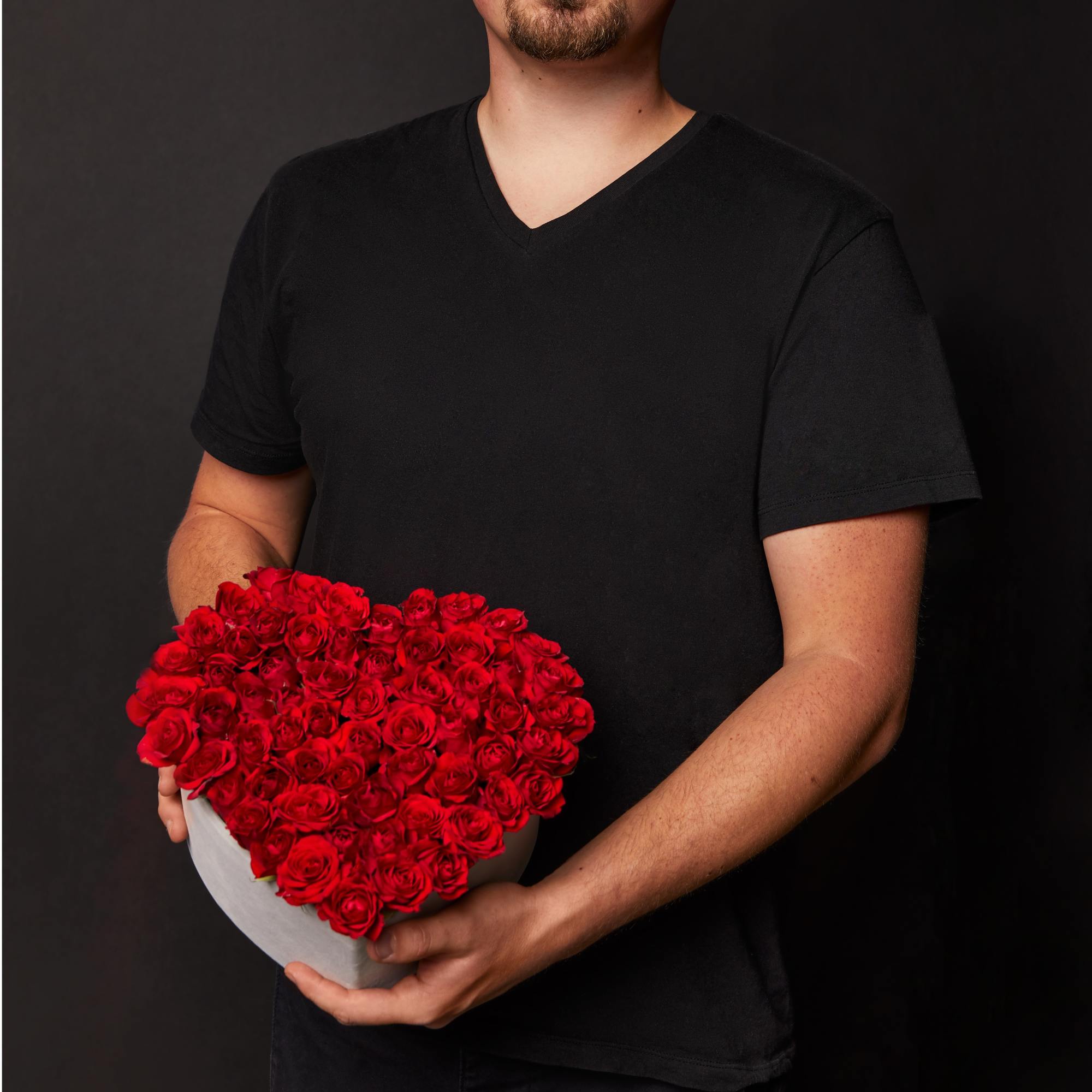 Man holding a heart-shaped box of red roses