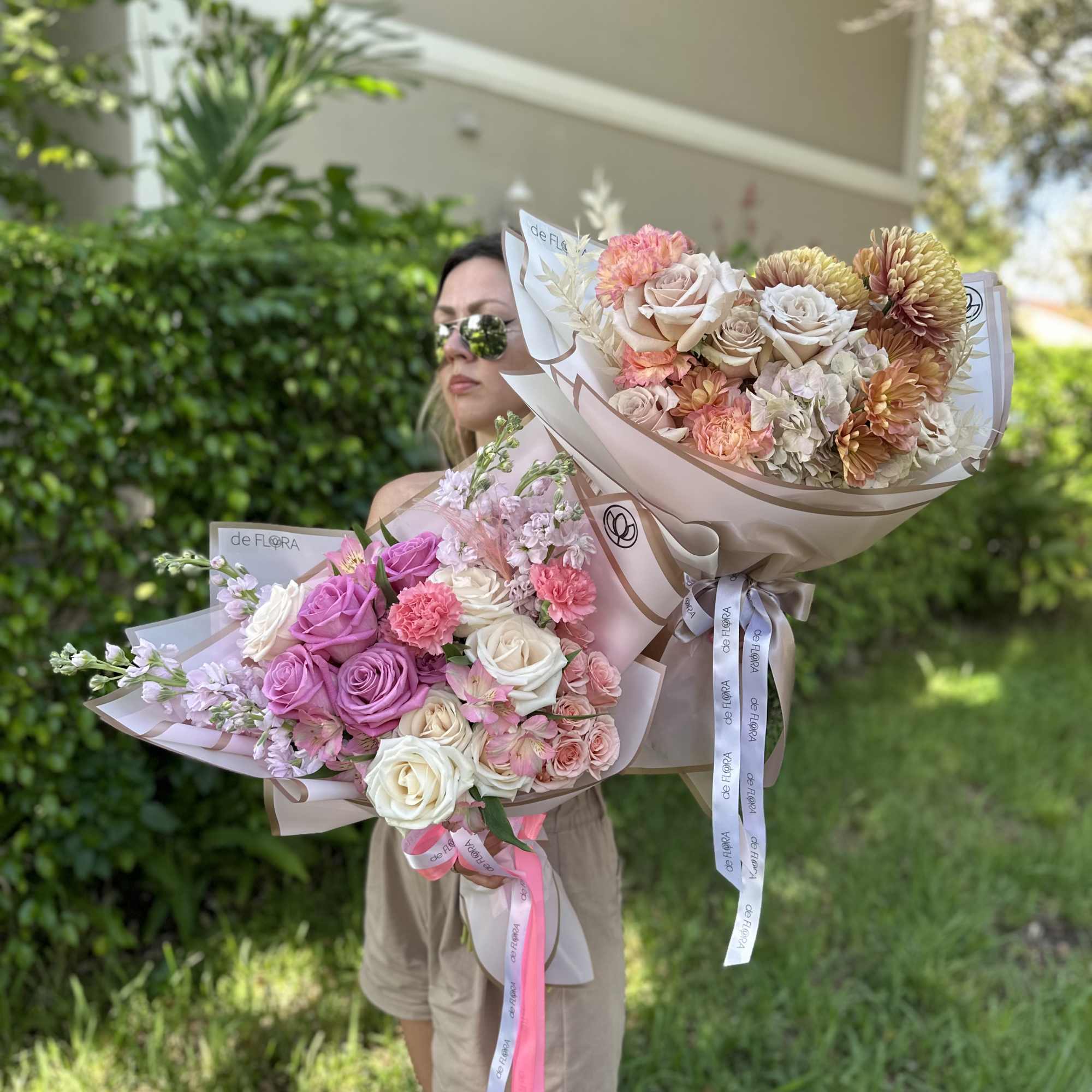 Two pastel rose bouquets with ribbon wraps held outdoors