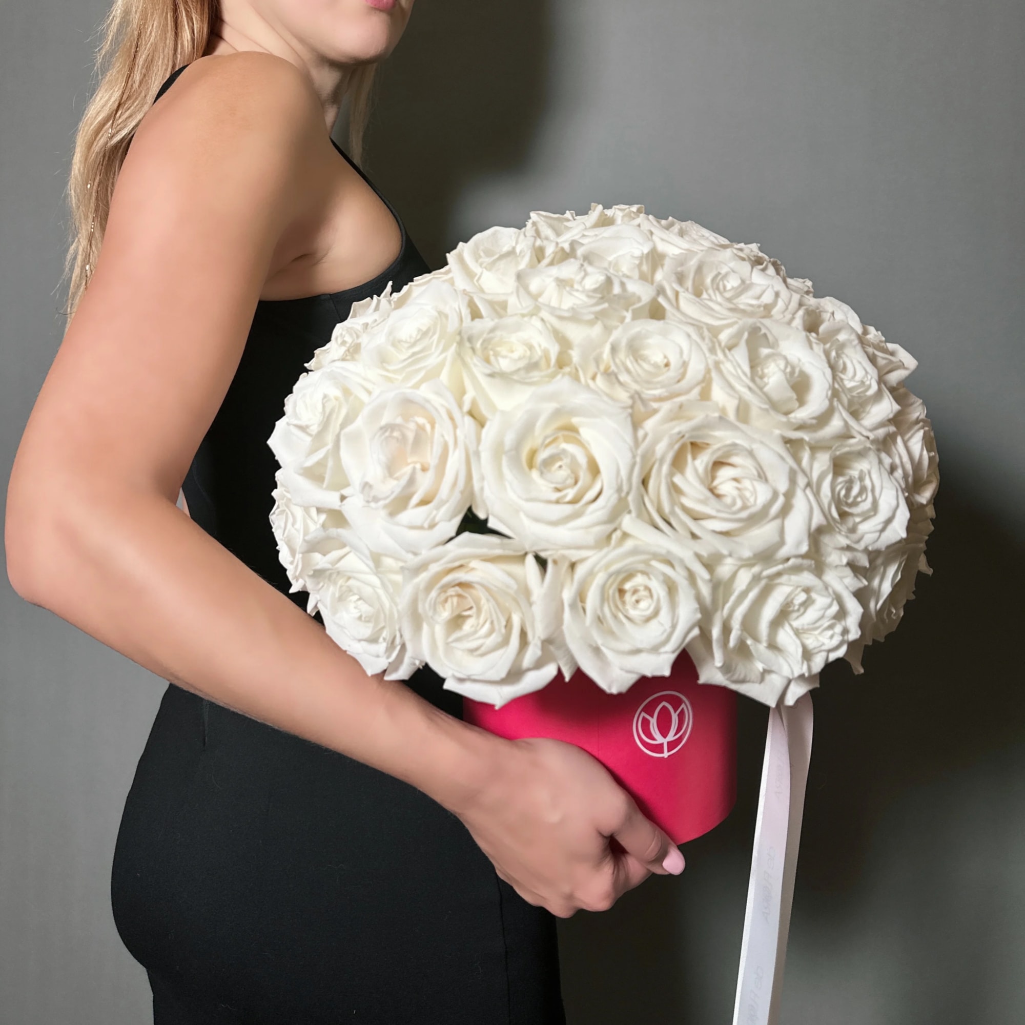 Woman holding a large bouquet of white roses in a pink box