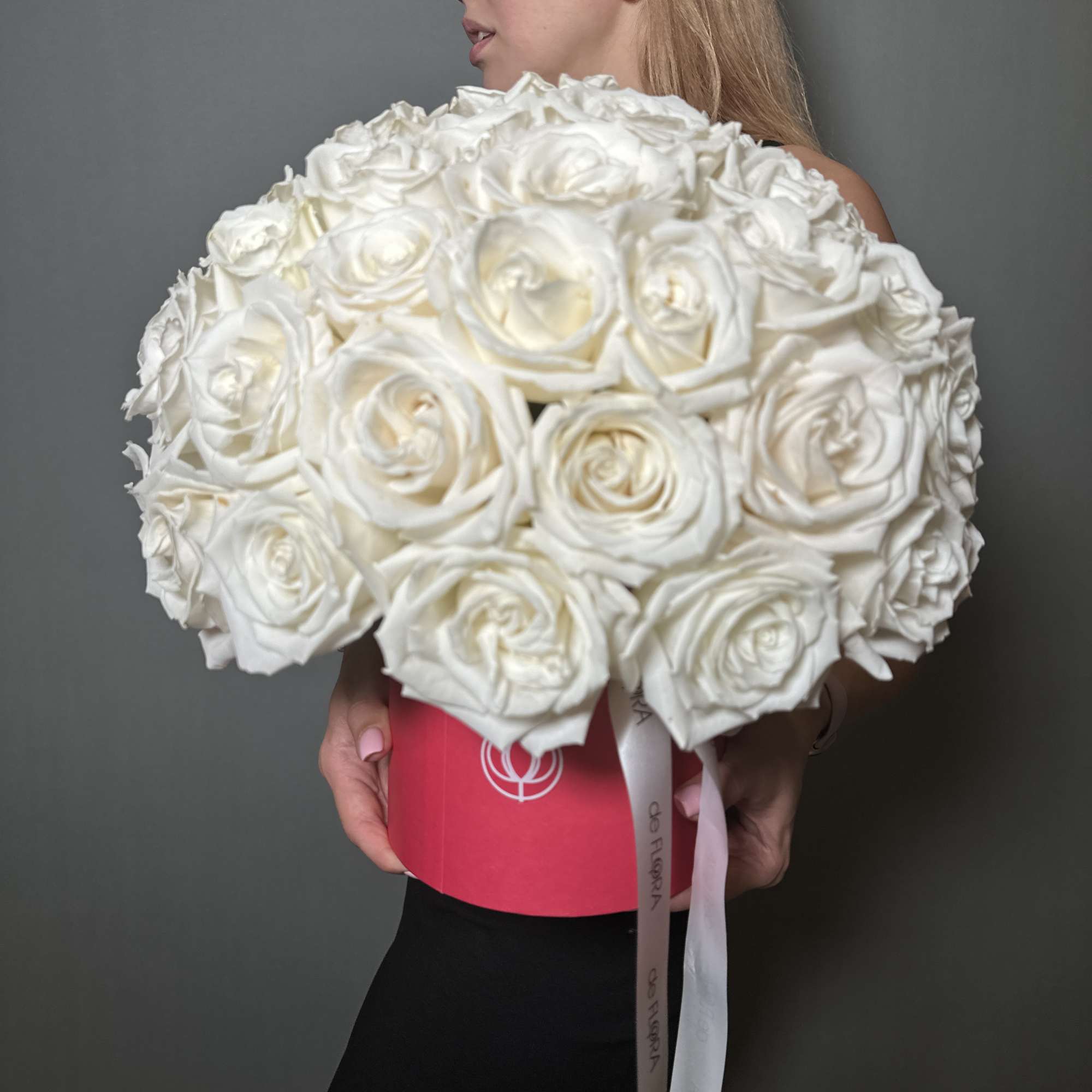 Large bouquet of white roses held against a gray background