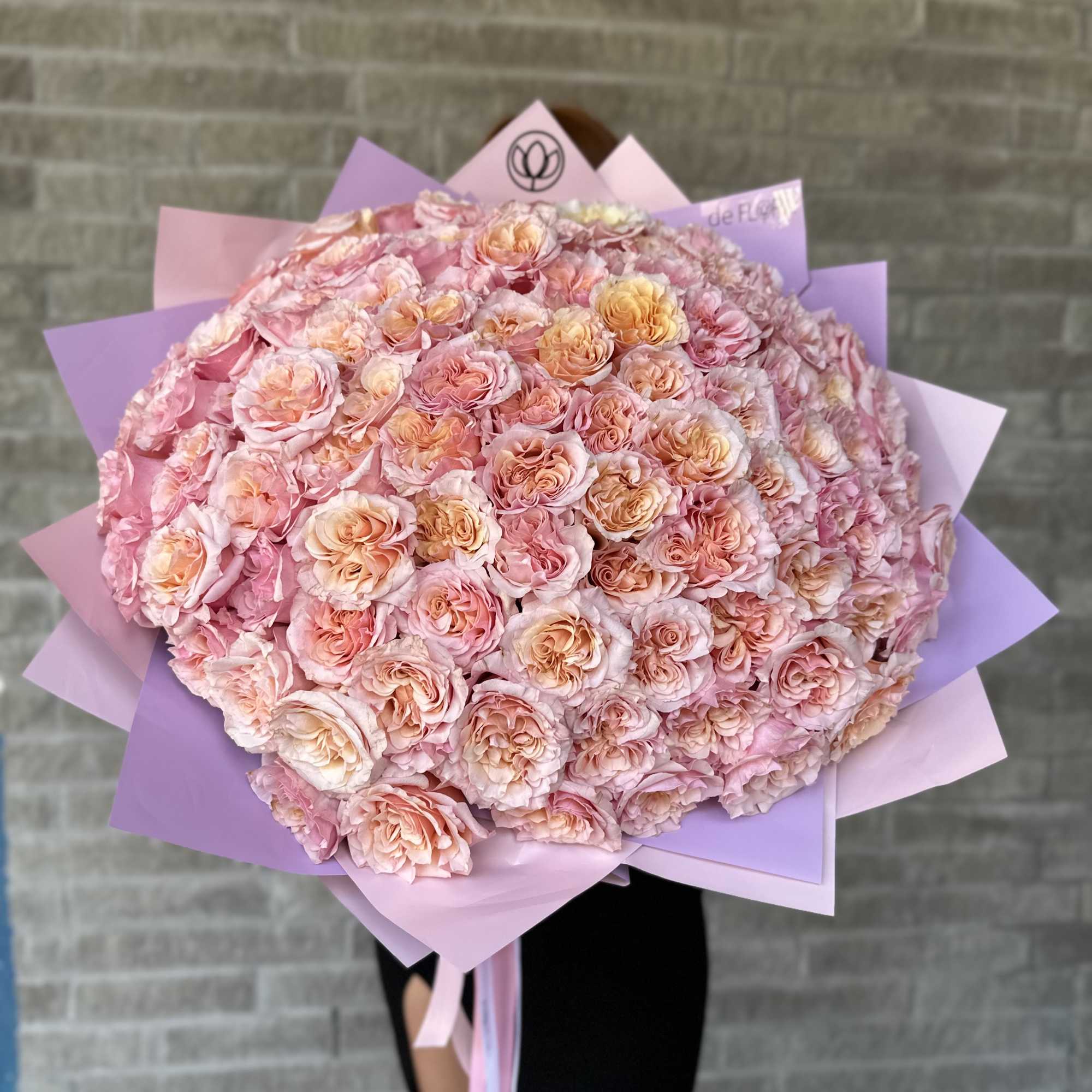 Large bouquet of pink and peach roses wrapped in lavender paper