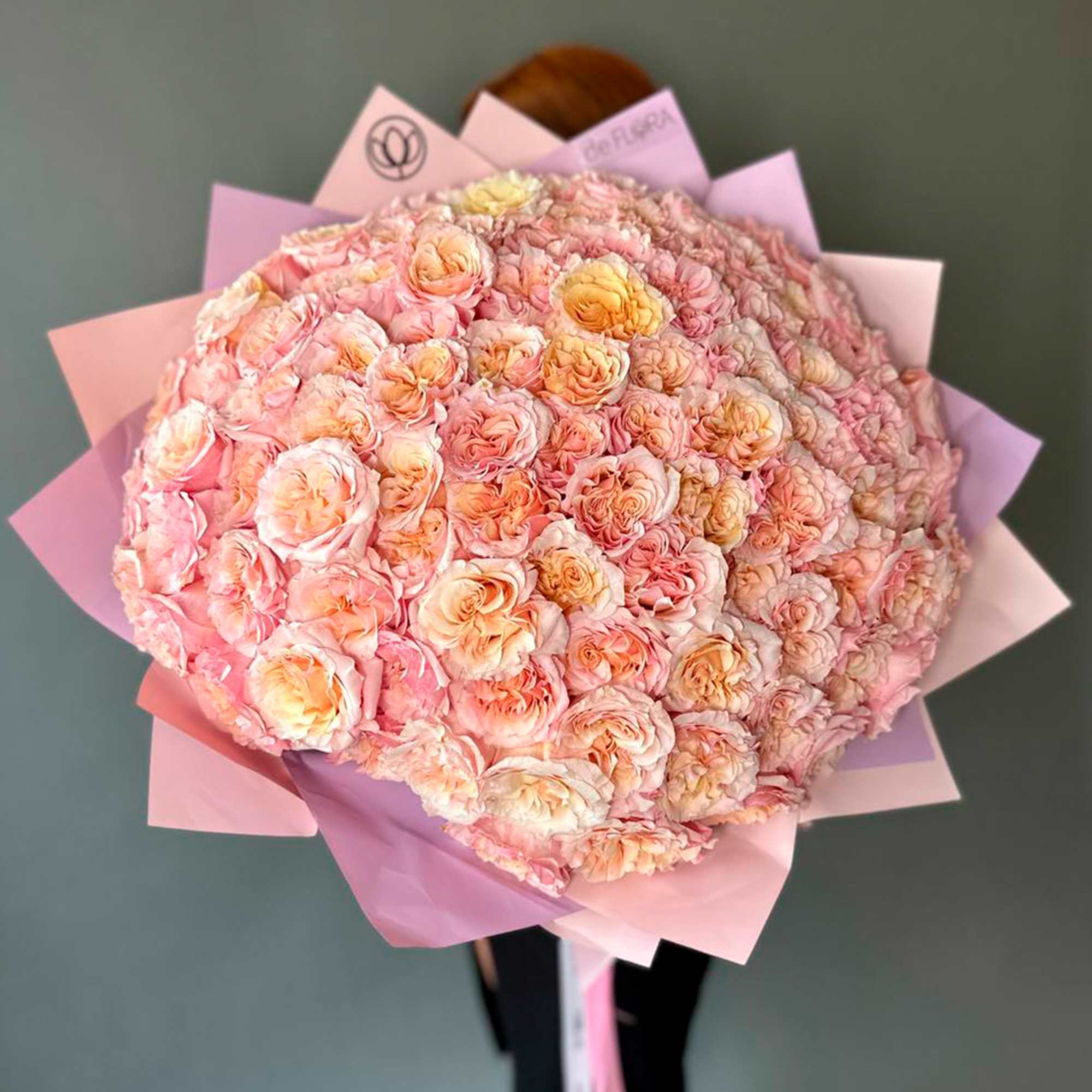 Large bouquet of pale pink and peach roses wrapped in pink paper