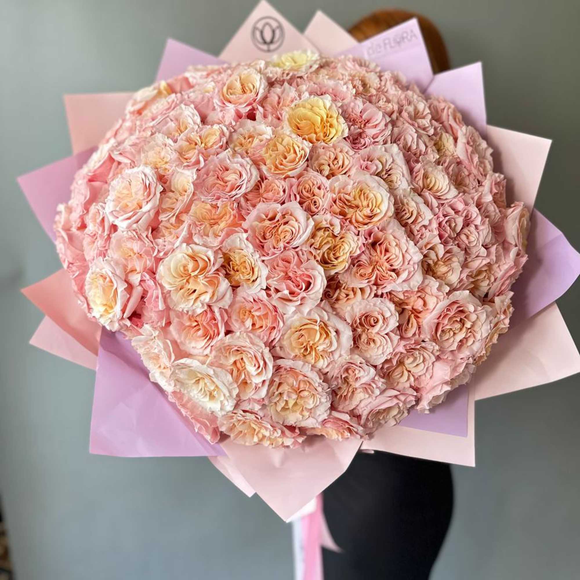 Large bouquet of pale pink and peach roses wrapped in pastel paper