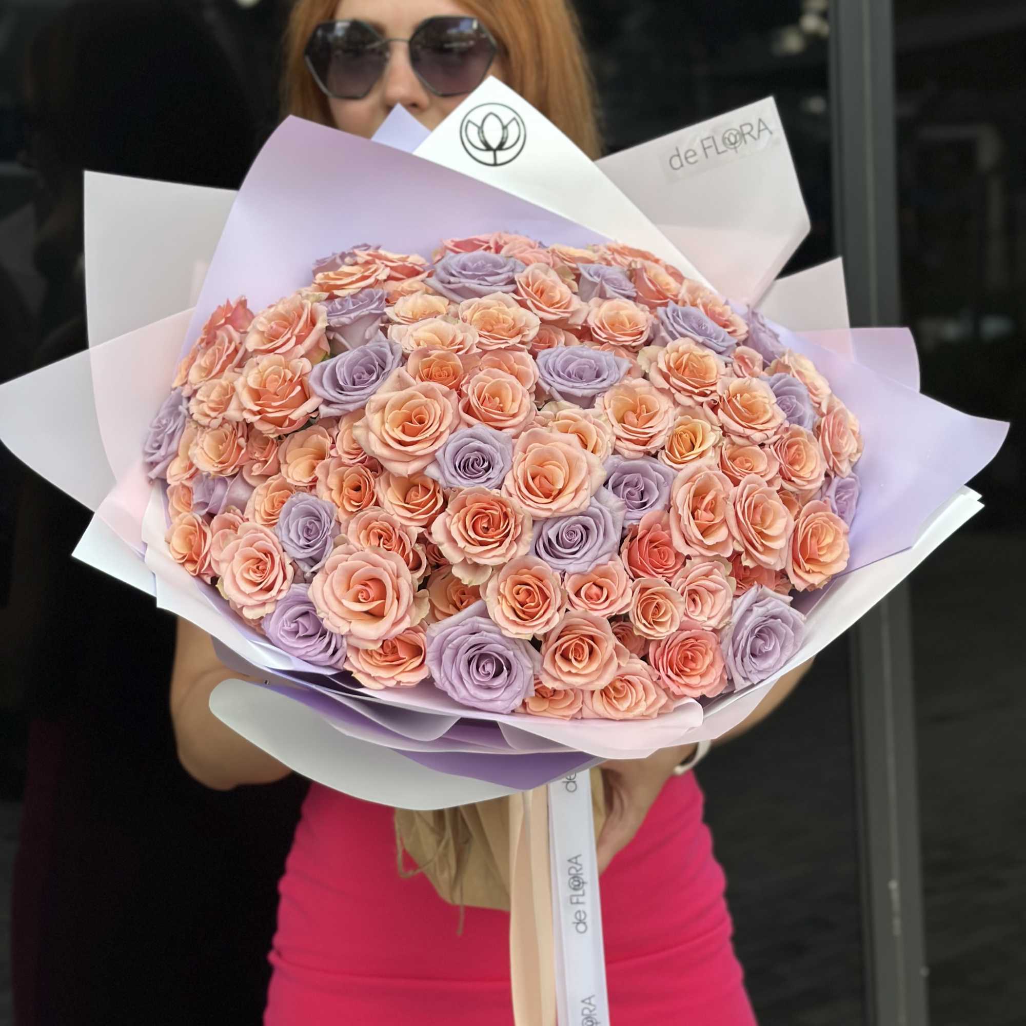 Large bouquet of peach and lavender roses wrapped in pastel paper