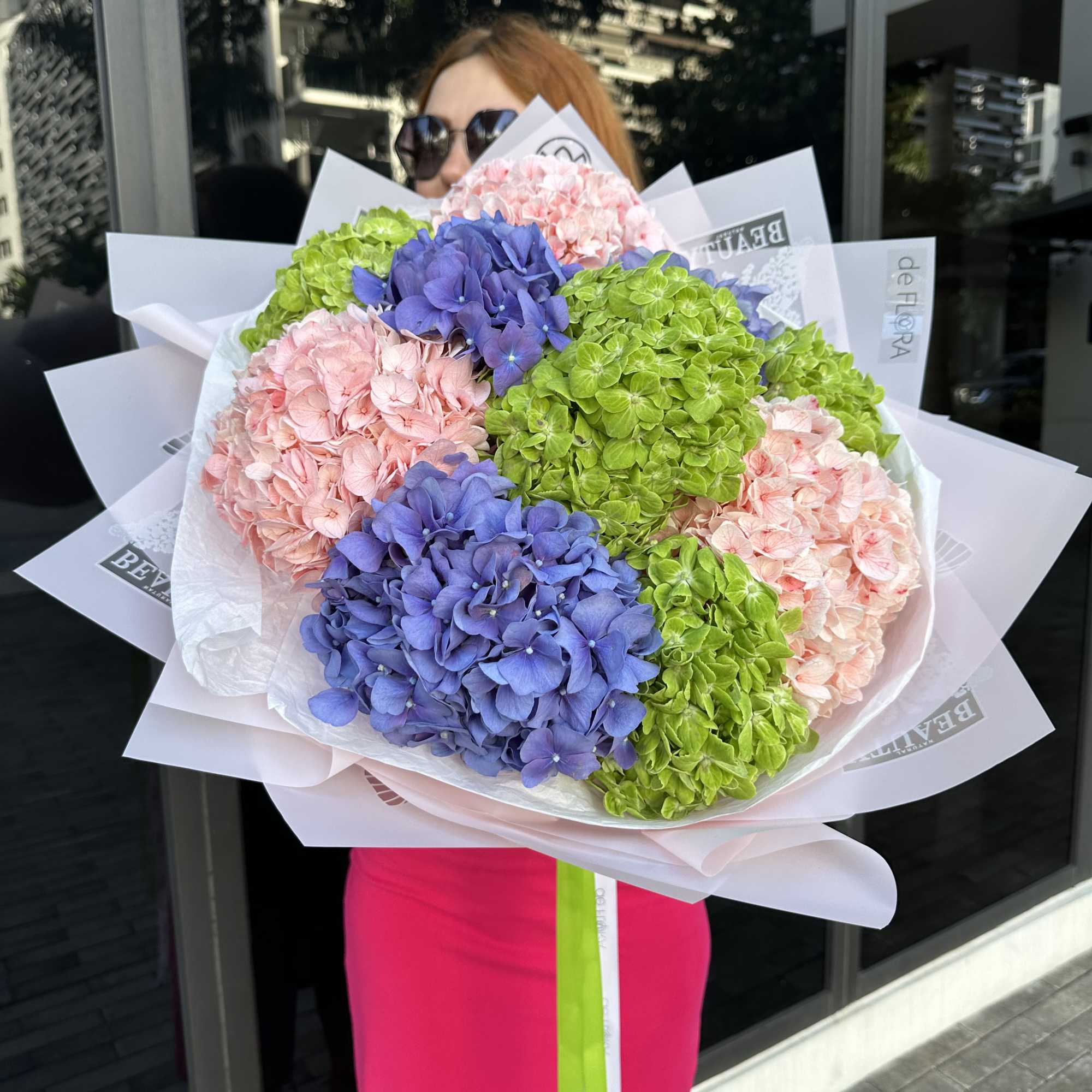 Large bouquet of pink, blue, and green hydrangeas wrapped in white paper