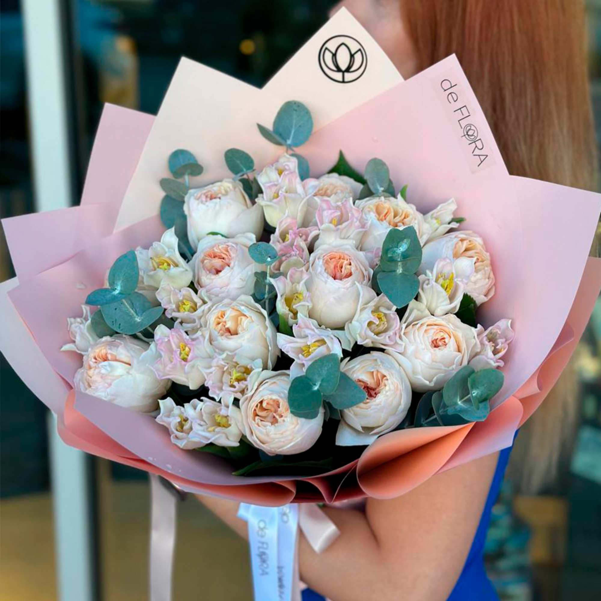Bouquet of pale pink and white roses wrapped in pink paper