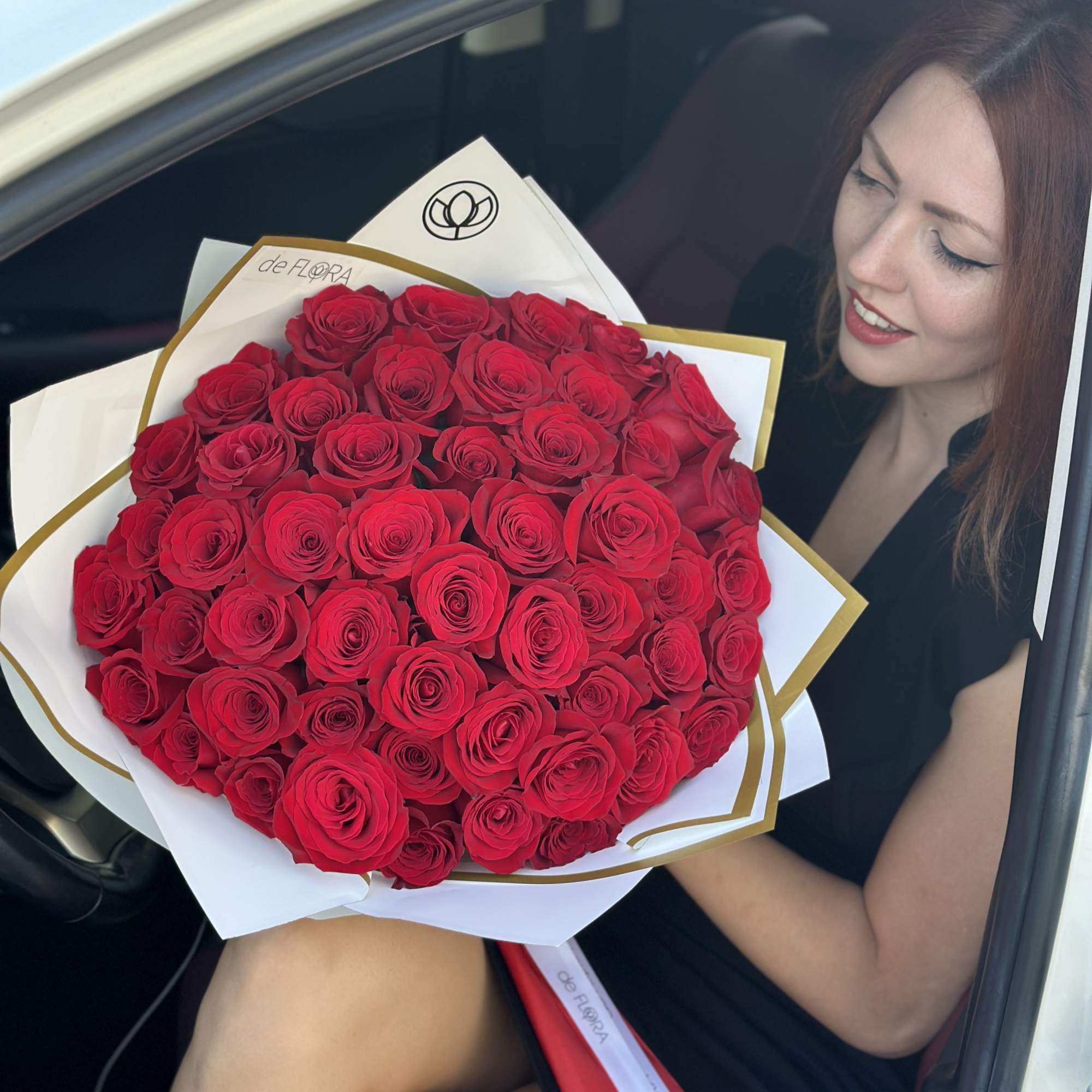 Large bouquet of red roses wrapped in white paper with gold trim
