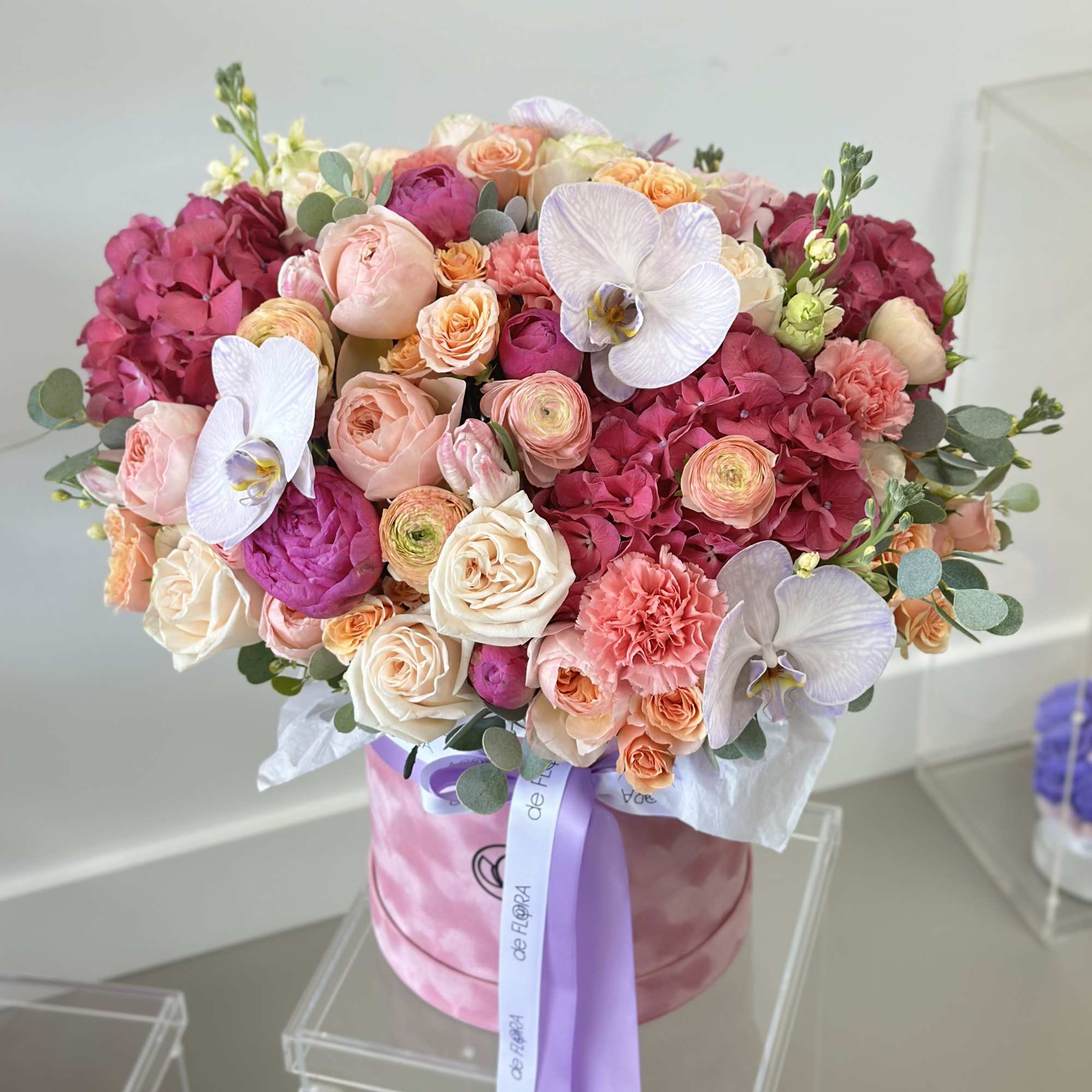 Large pink and peach bouquet in a round box with lavender ribbon