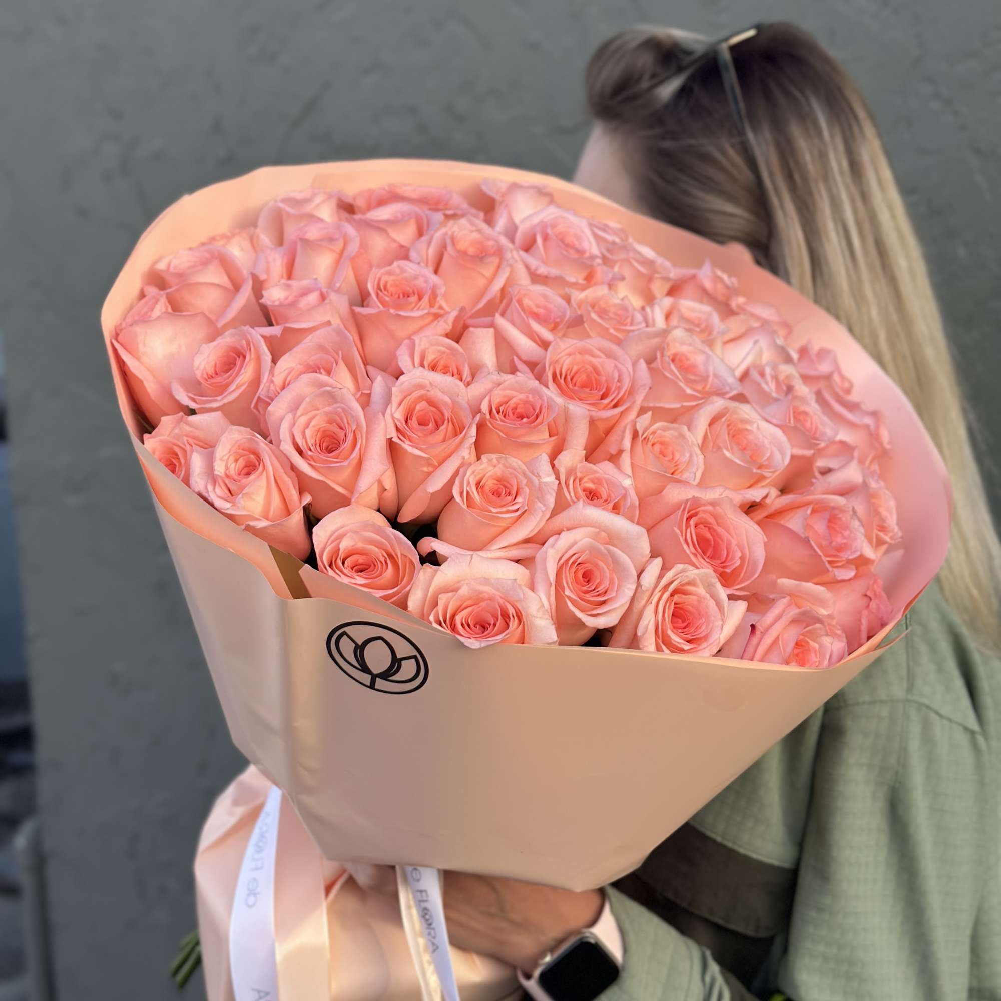 Large bouquet of peach-pink roses wrapped in blush paper