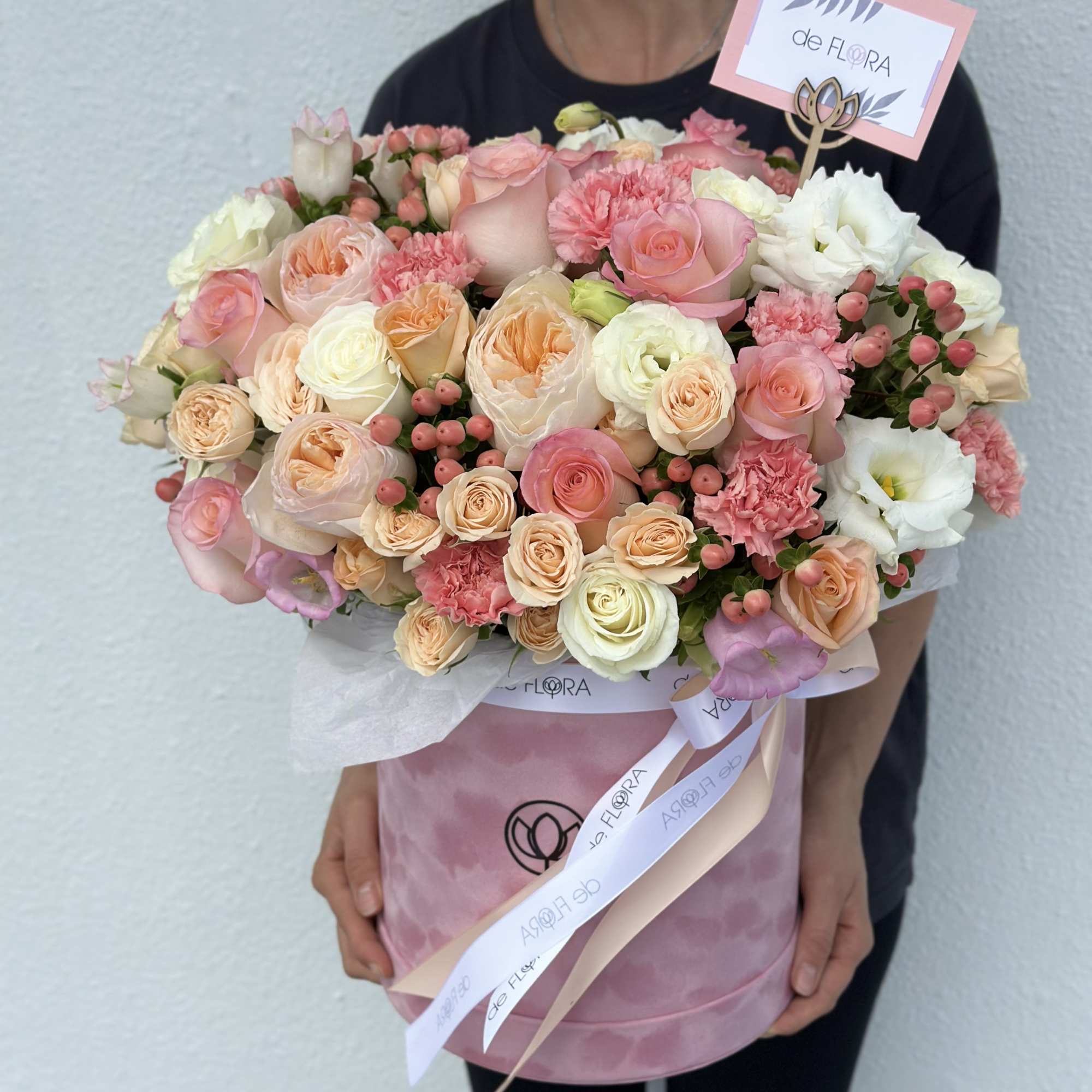 Large pastel bouquet of roses, carnations, and white blooms in pink wrapping