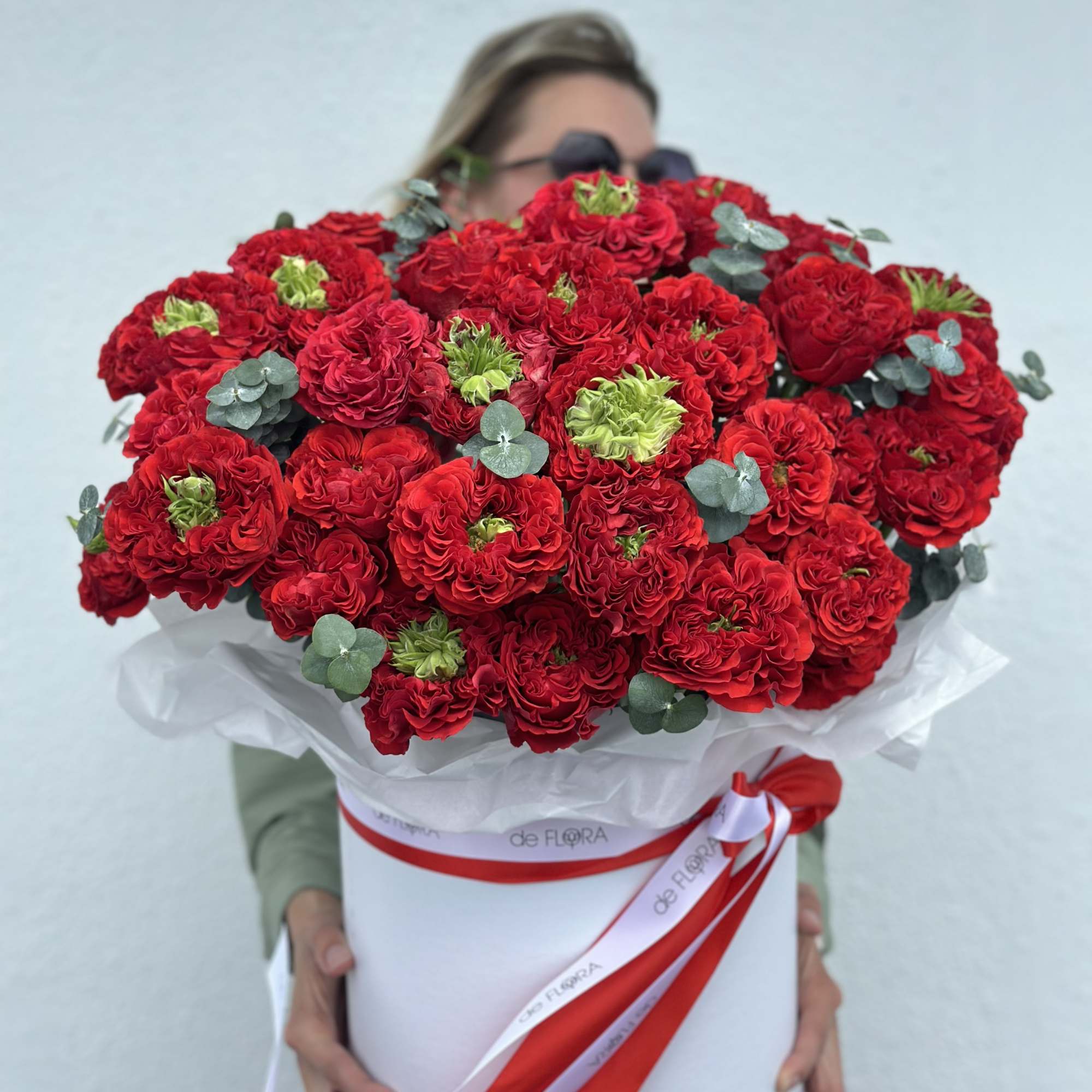 Large bouquet of red roses in a white hatbox with ribbon