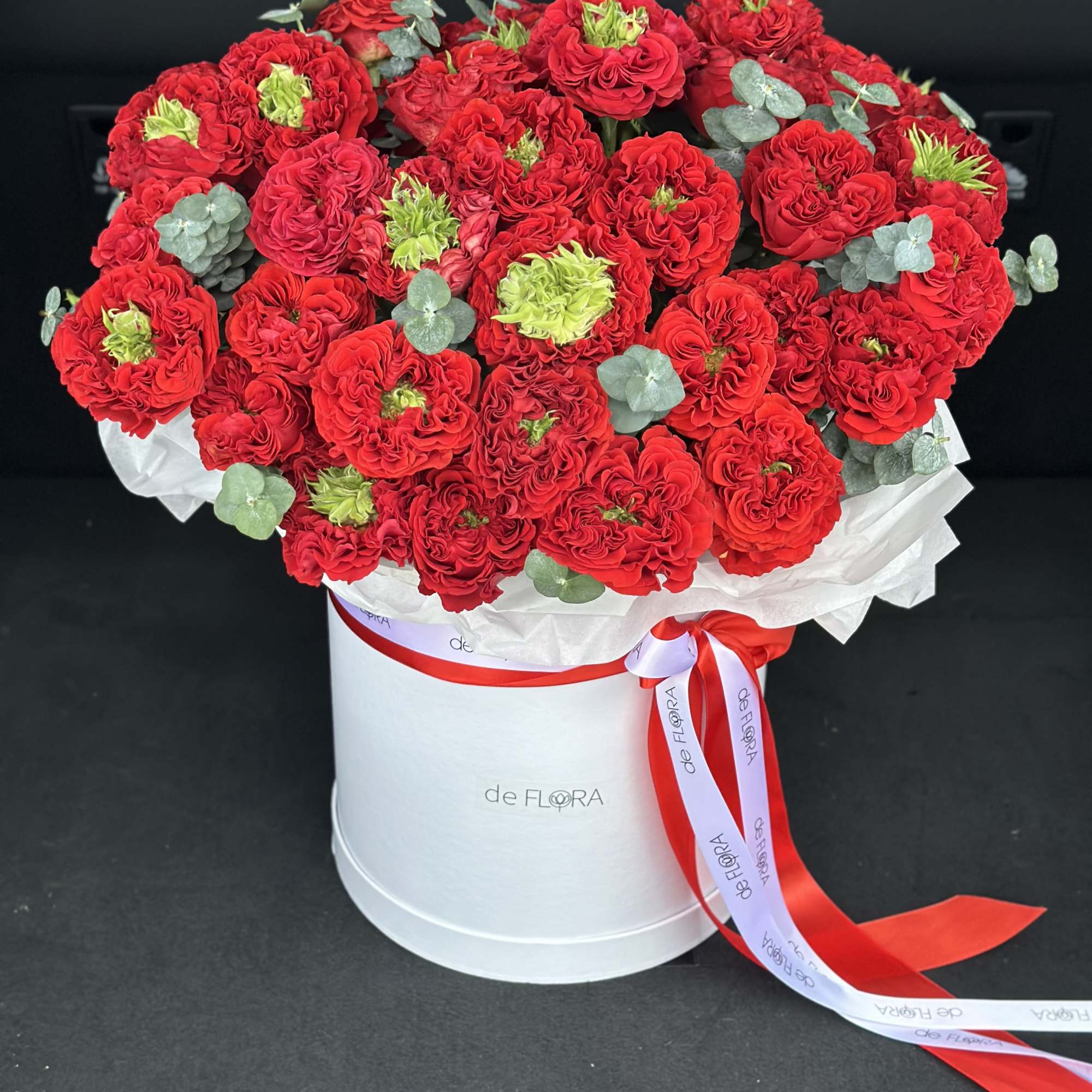 Large bouquet of red carnations in a white hatbox with ribbon