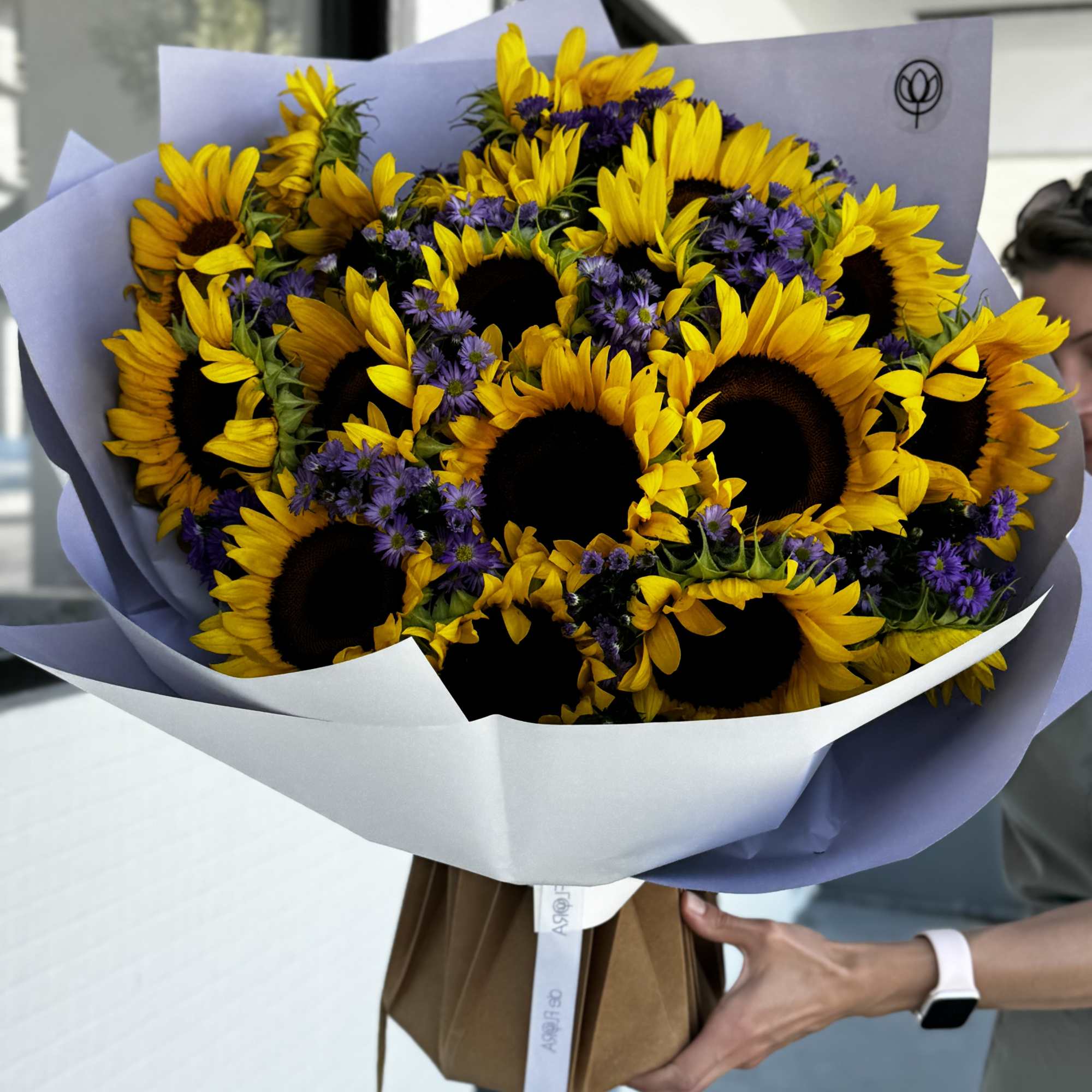 Bouquet of sunflowers and purple asters wrapped in lavender paper