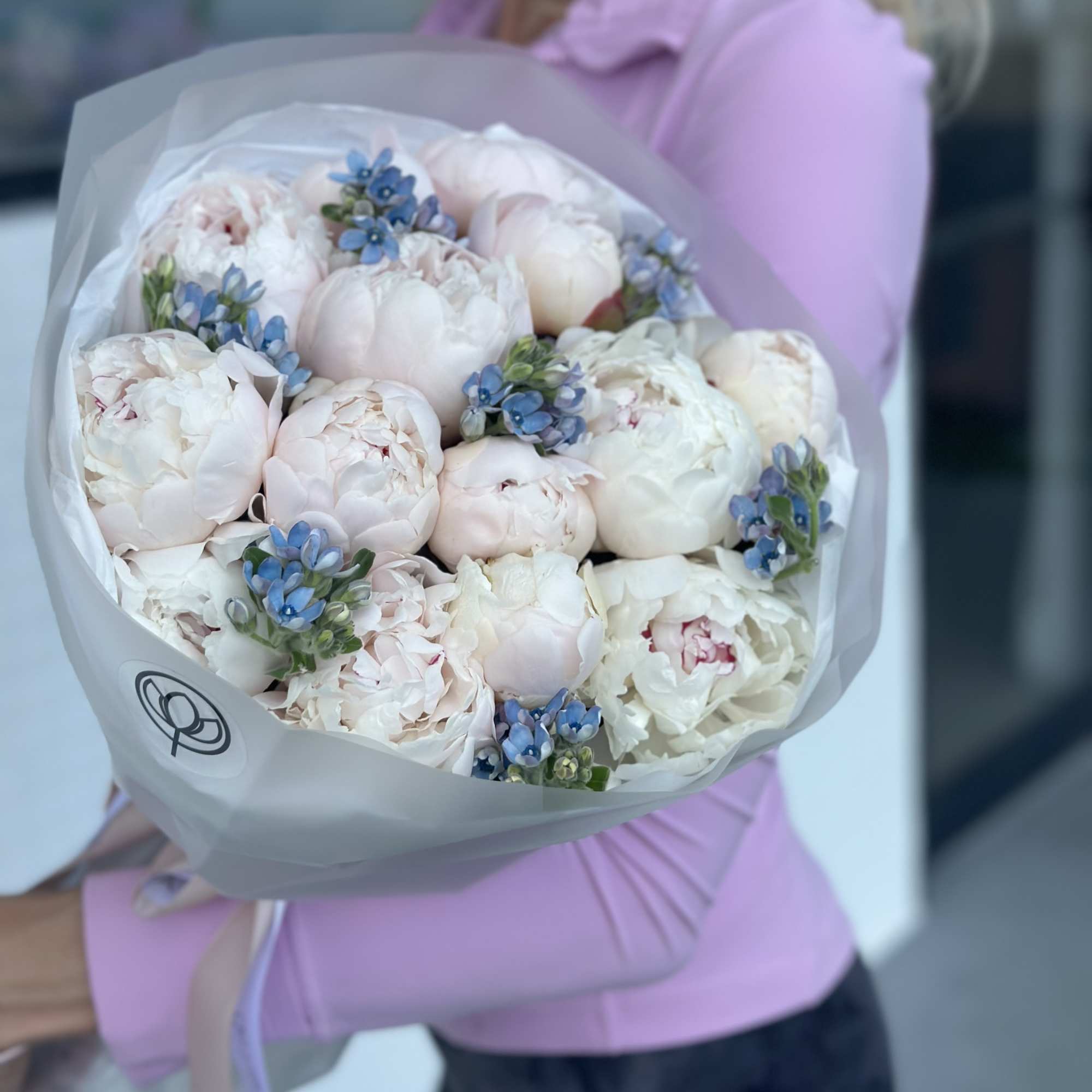 Bouquet of pale pink and white peonies with small blue accents