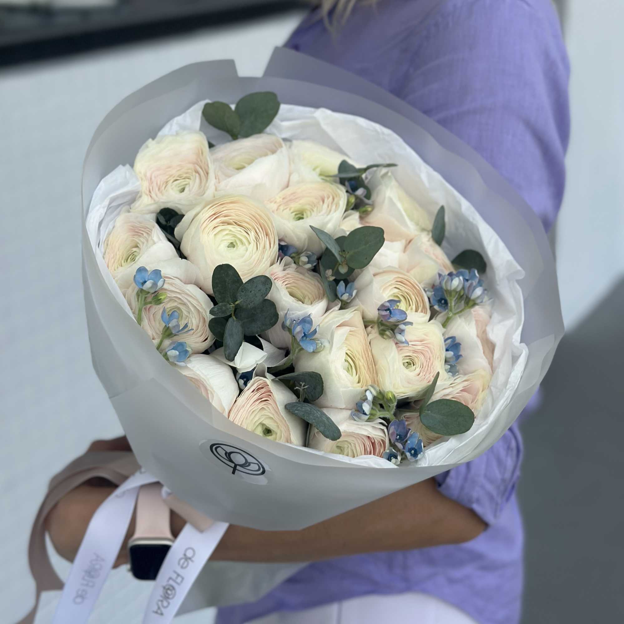 Bouquet of pale ranunculus with blue accents and eucalyptus