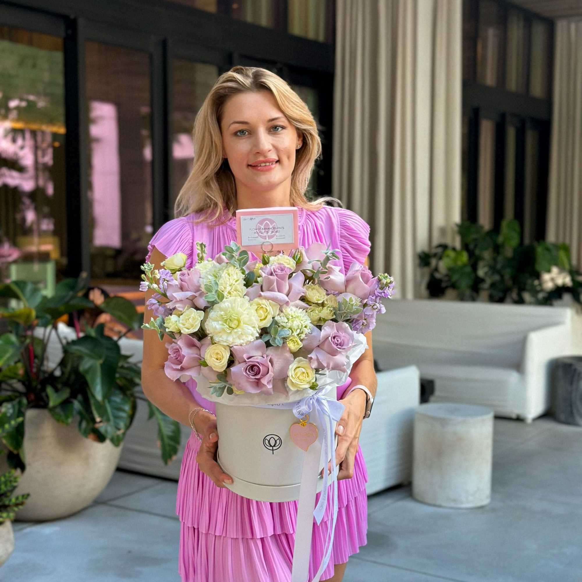 Woman holding a pastel flower arrangement in a white hat box