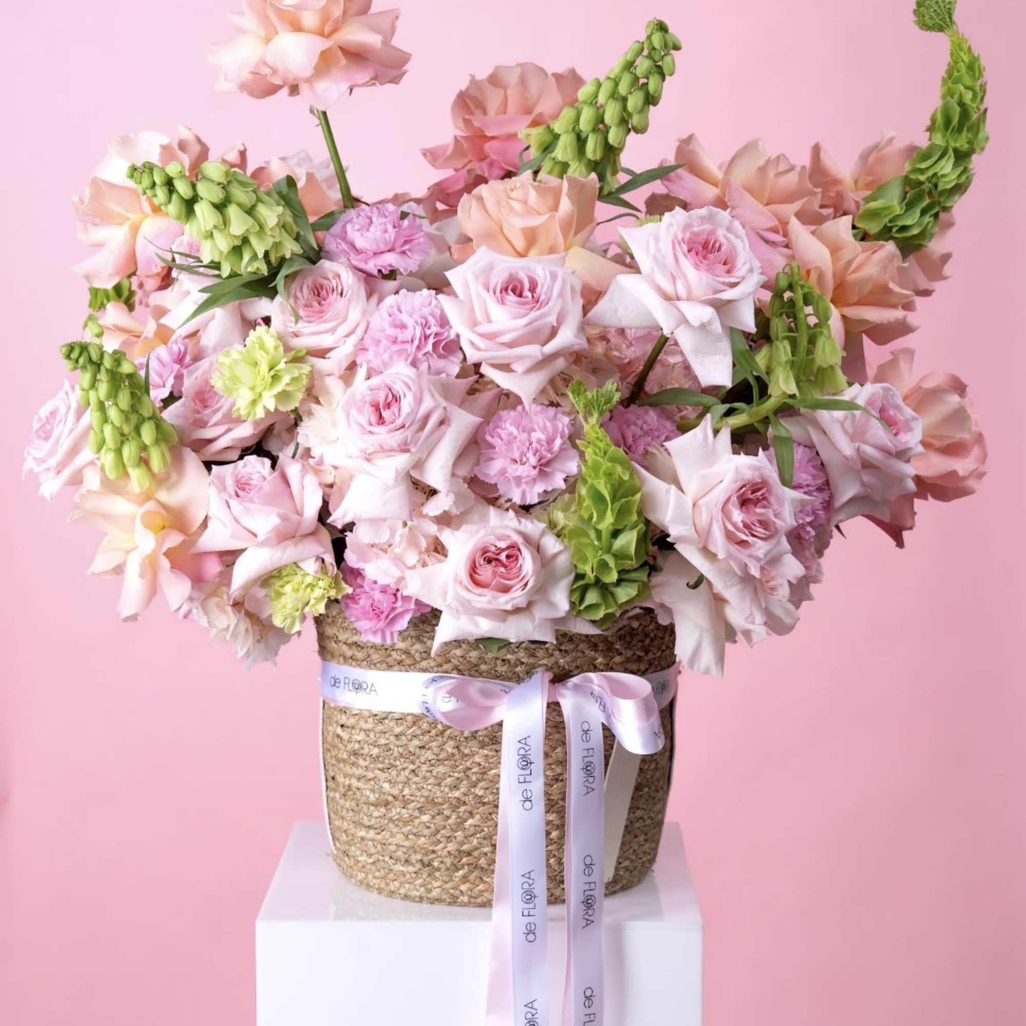 Soft blush and peach roses mingle with ruffled pink carnations in a