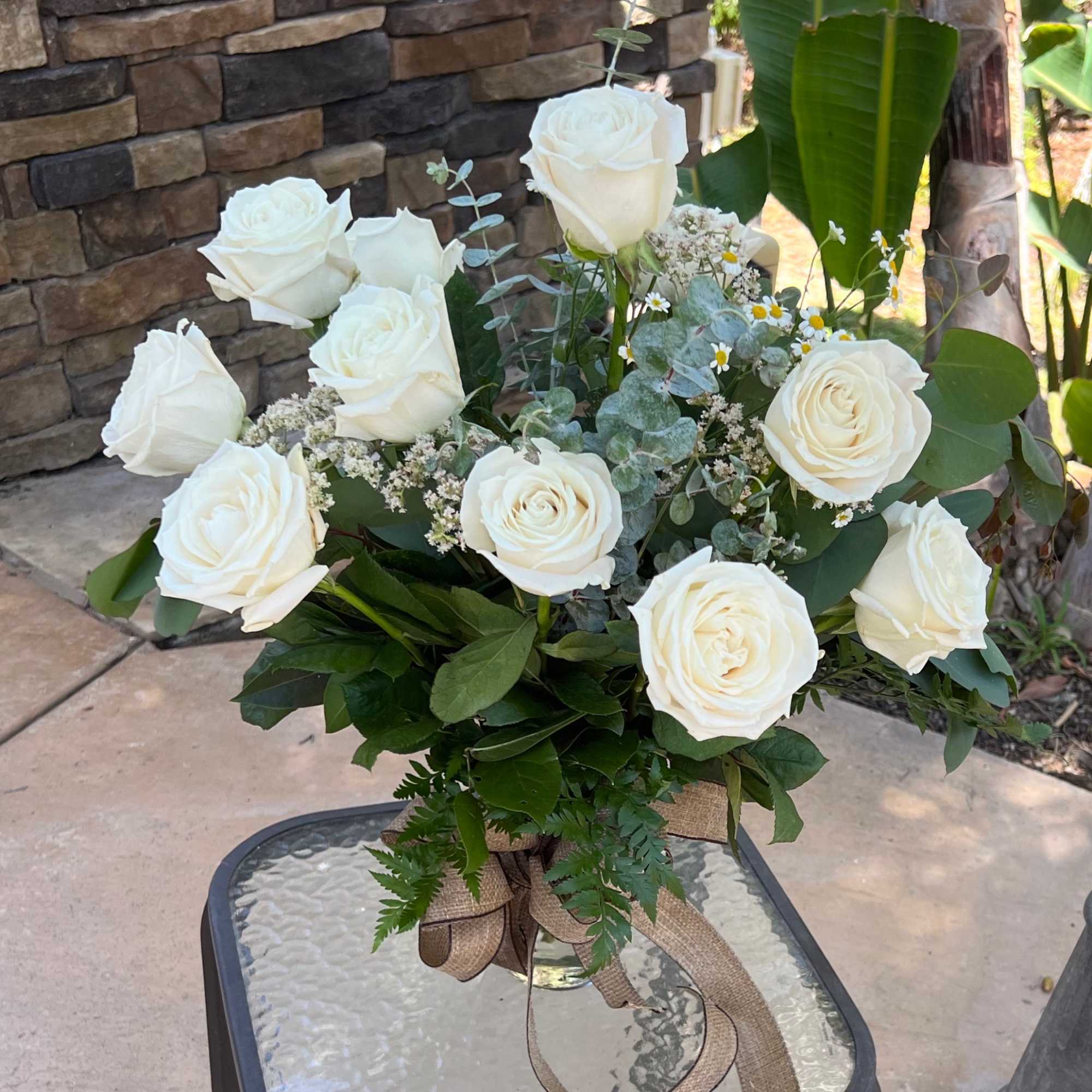 White rose bouquet in a glass vase with burlap ribbon