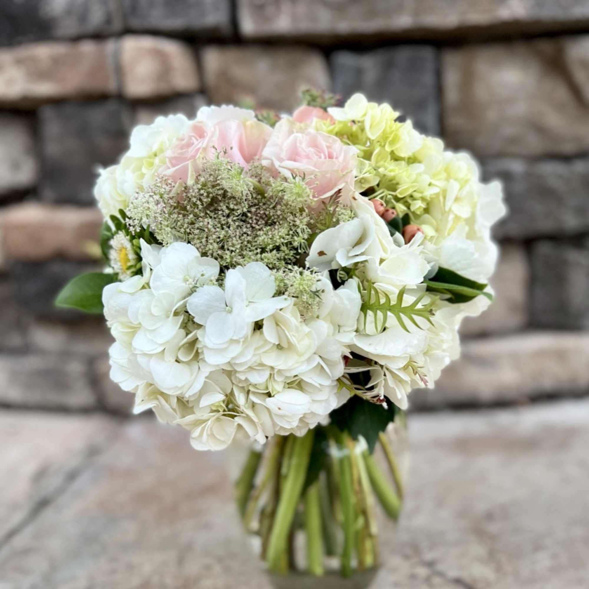 Bouquet of white hydrangeas and pale pink roses in a glass vase
