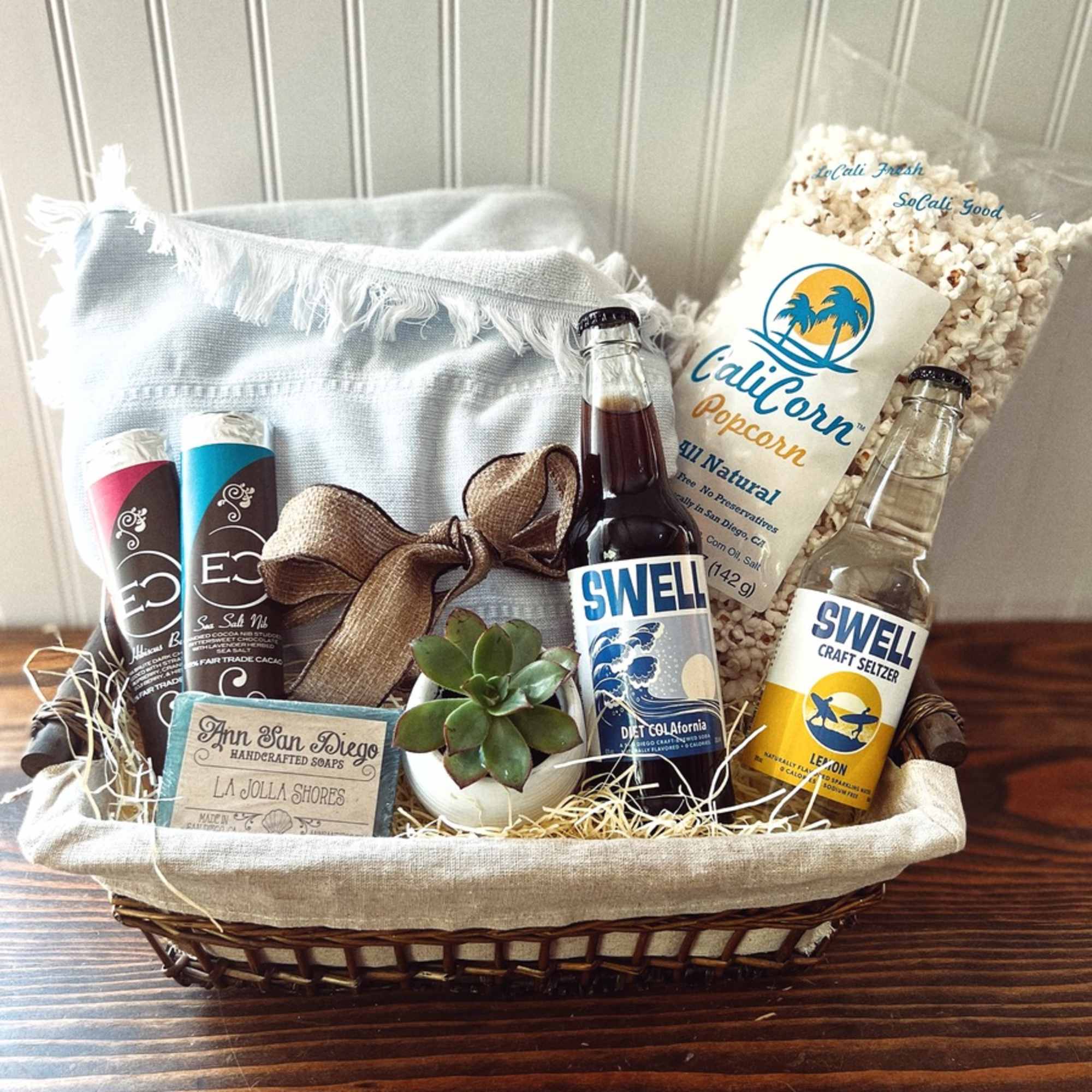 Gift basket with popcorn, soda bottles, soap, and a small succulent