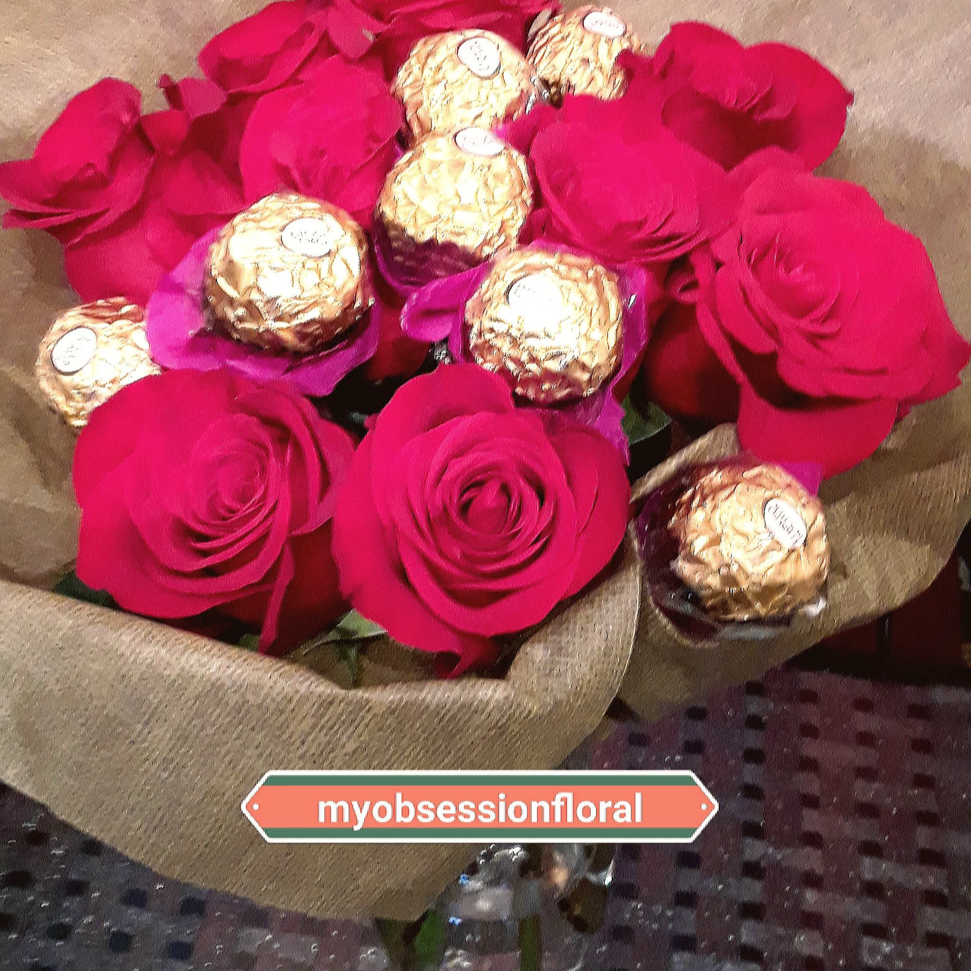 Bouquet of hot pink roses with gold-wrapped chocolates in brown paper