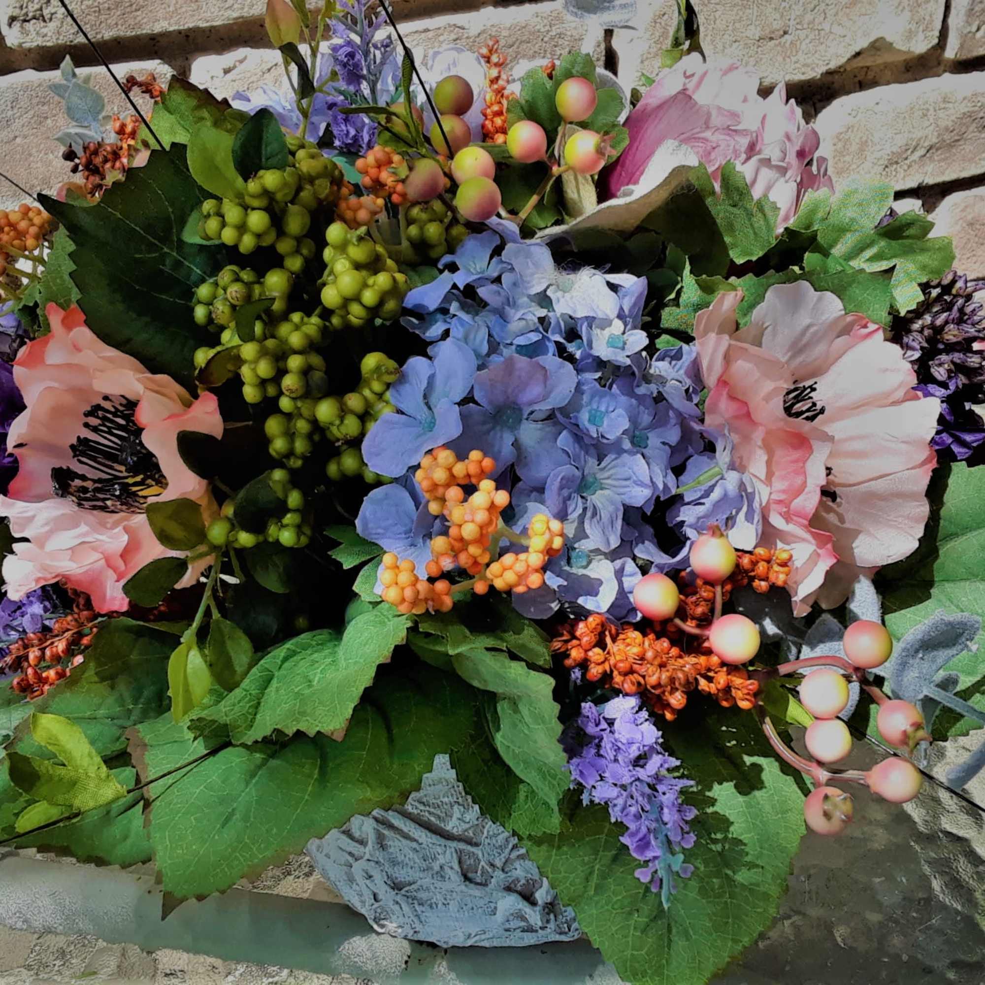 Mixed bouquet with pastel flowers and berries against a brick wall