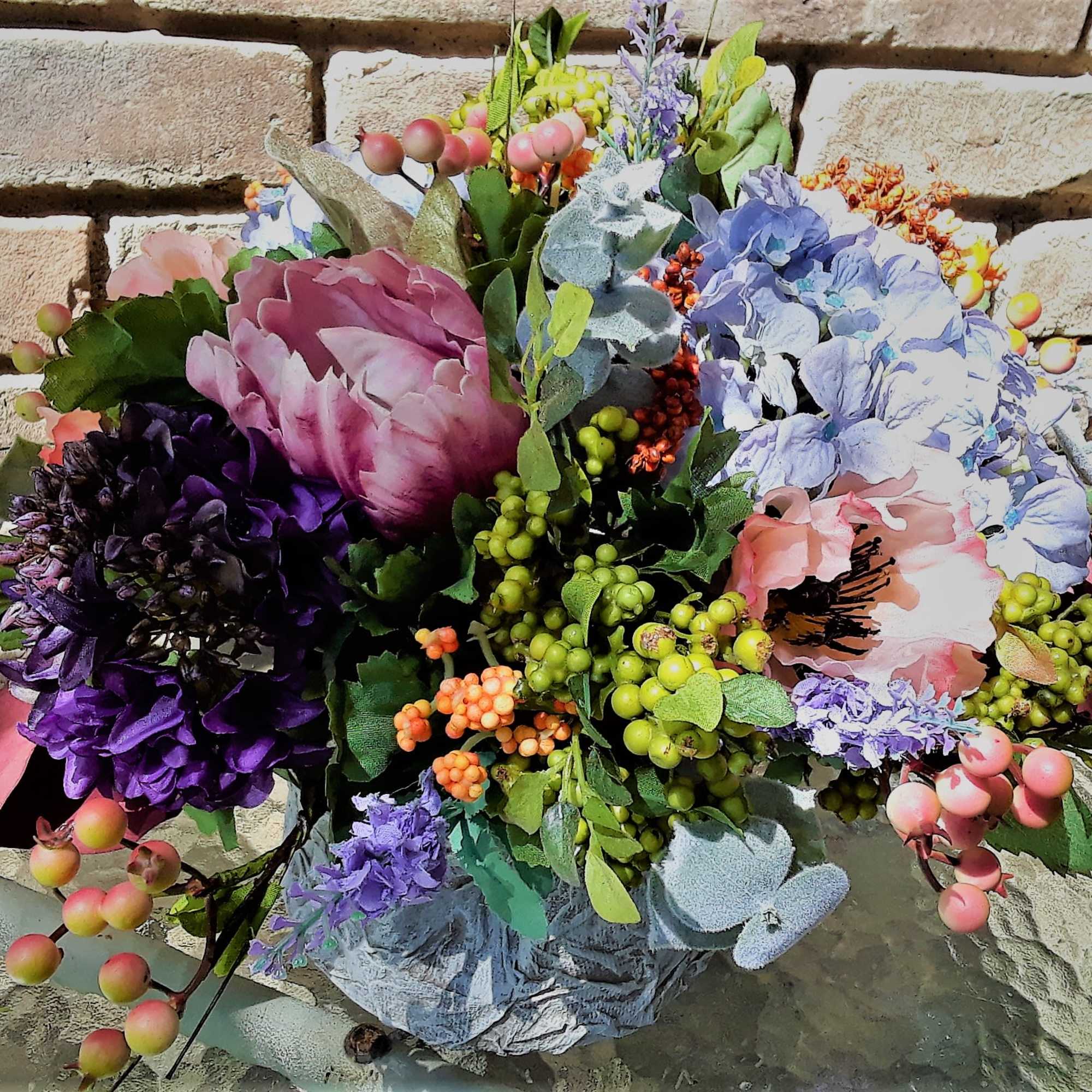 Colorful bouquet with pink, purple, and blue flowers against a brick wall