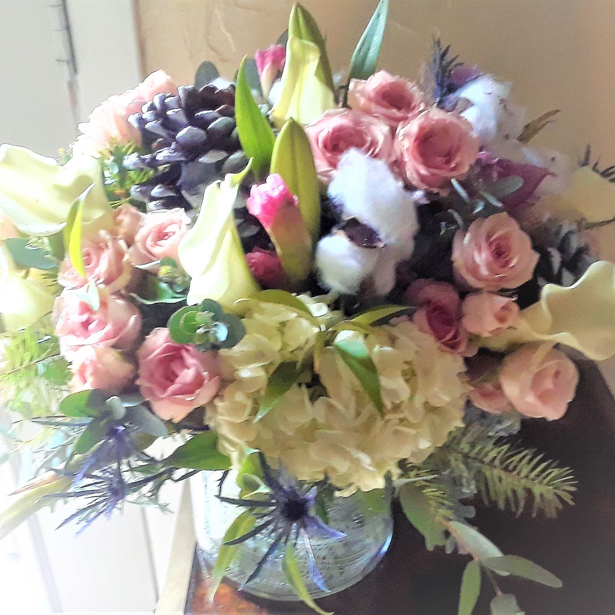 Bouquet of pink roses, white lilies, and hydrangeas in a glass vase