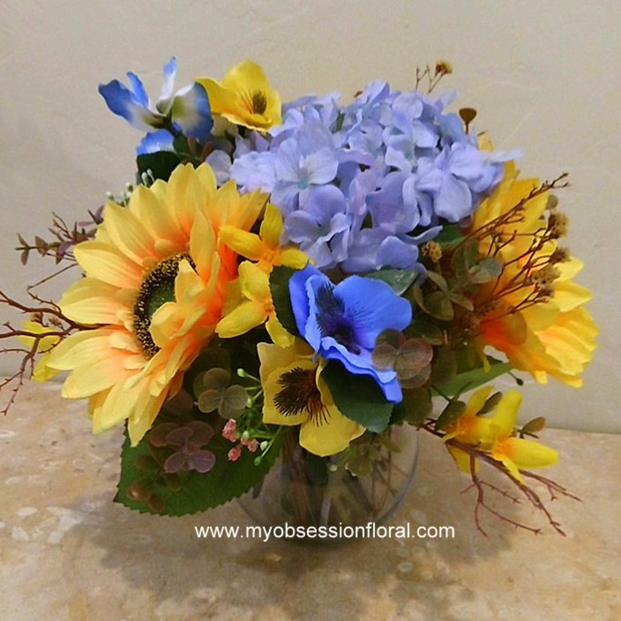 Bouquet of yellow sunflowers and blue flowers in a glass vase