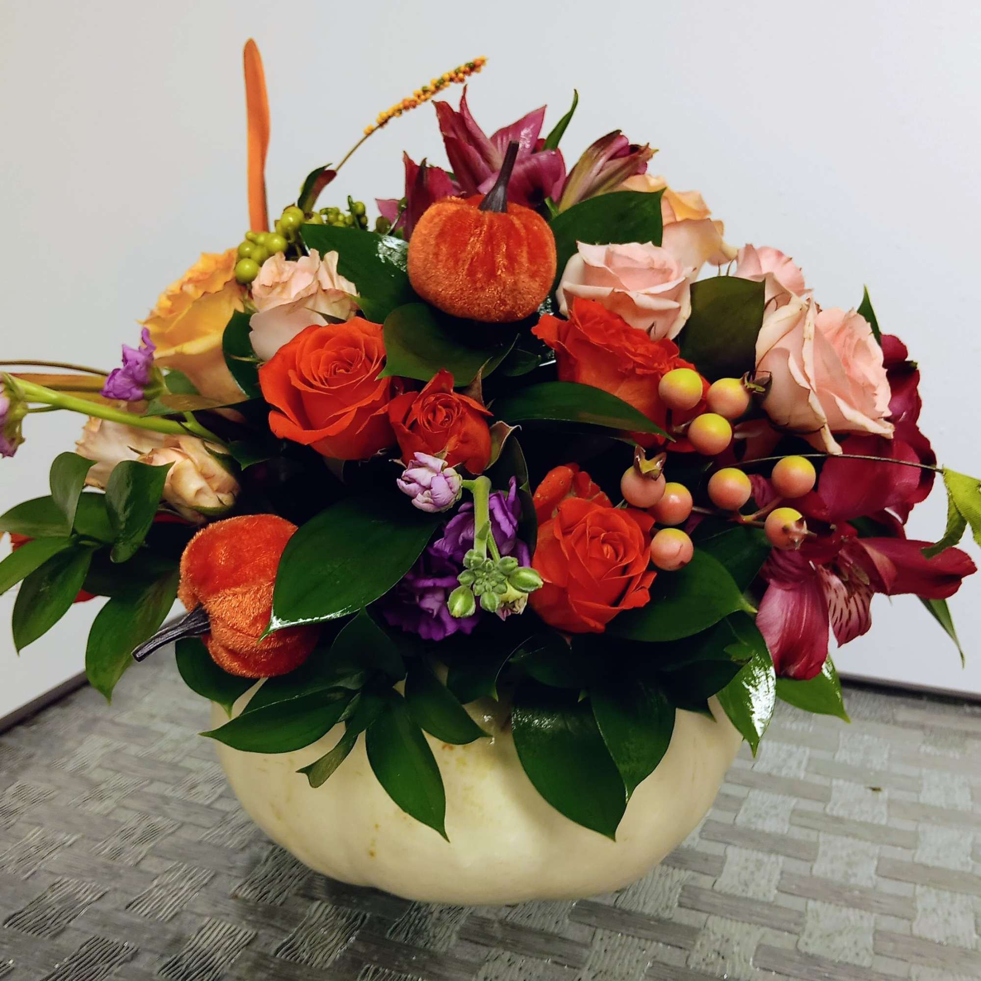 Autumn floral arrangement with roses and lilies in a cream bowl