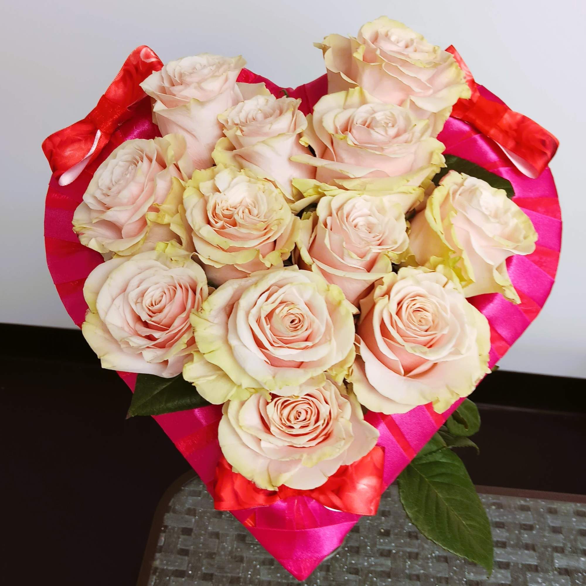 Bouquet of pale pink roses wrapped in bright pink and red paper