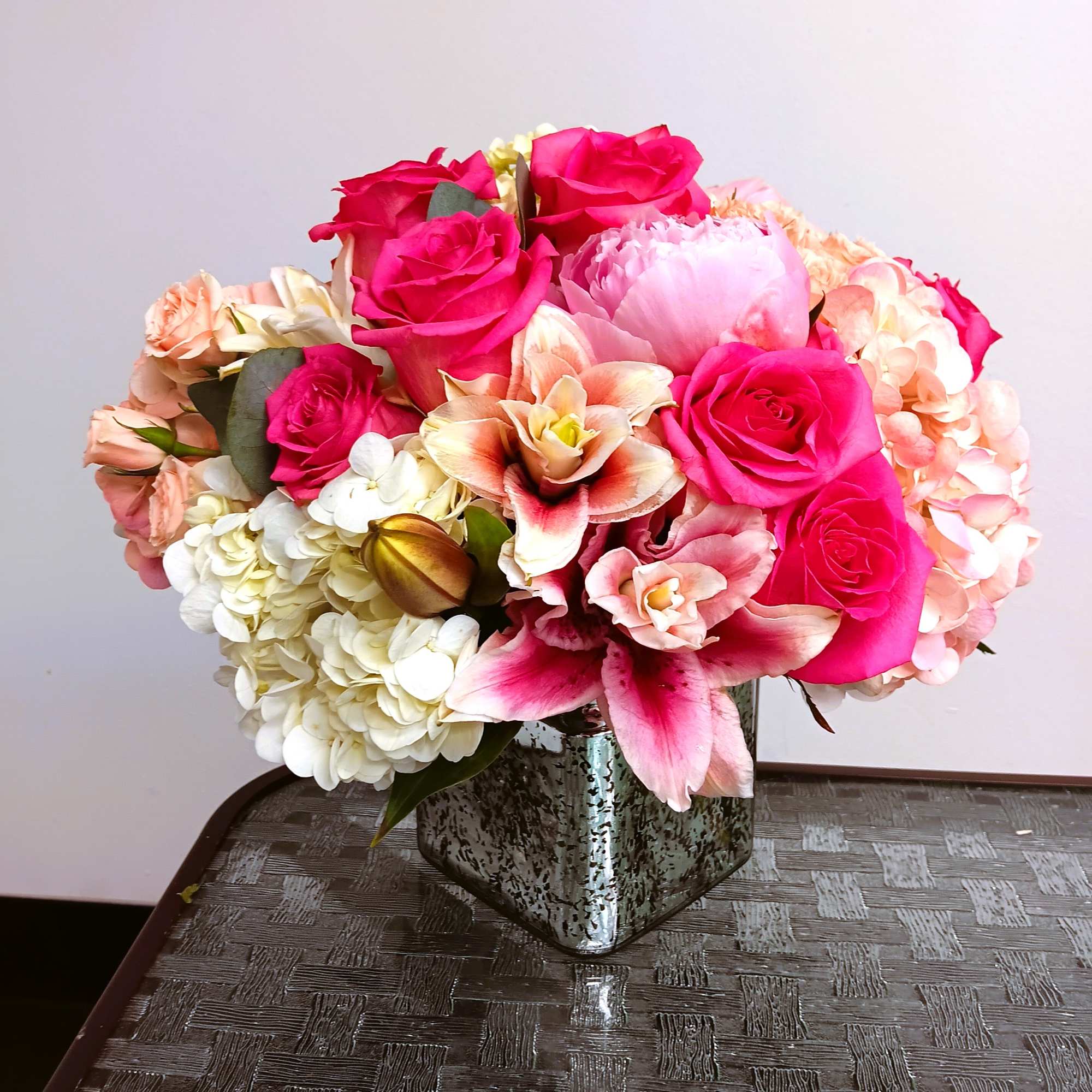 Pink and peach floral arrangement in a silver vase