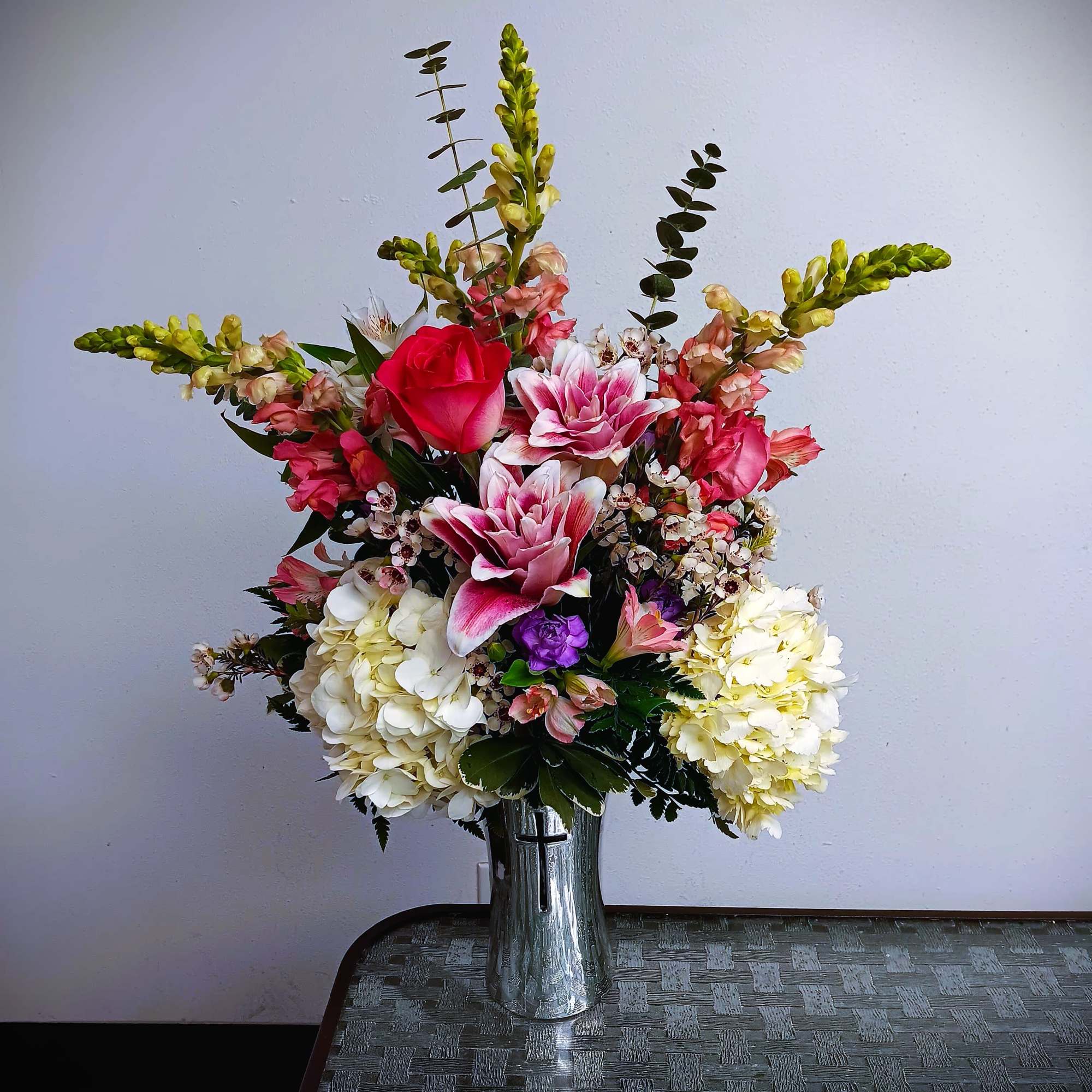 Tall mixed flower arrangement in a silver vase with pink, white, and yellow blooms