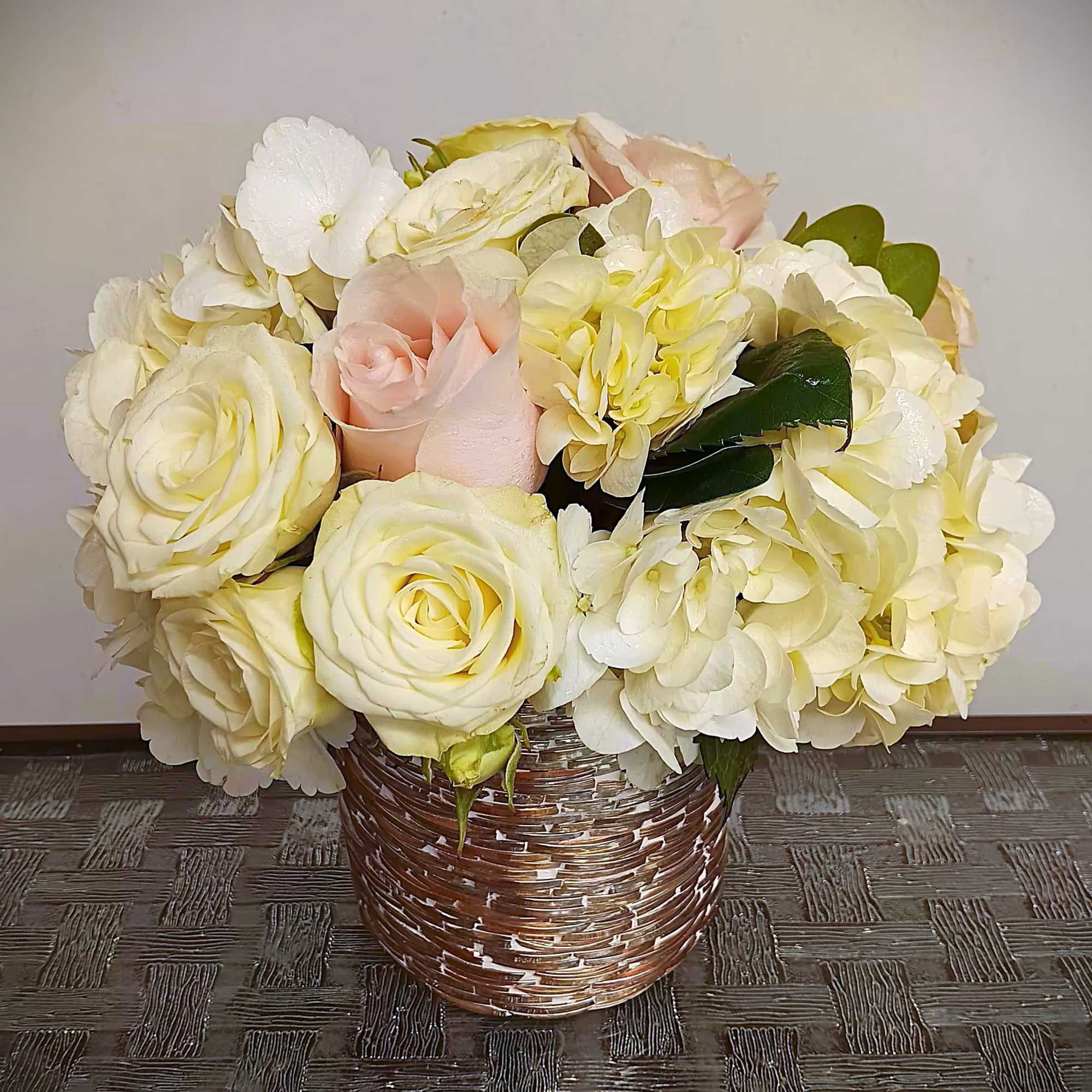 Cream and blush roses with white hydrangeas in a woven basket