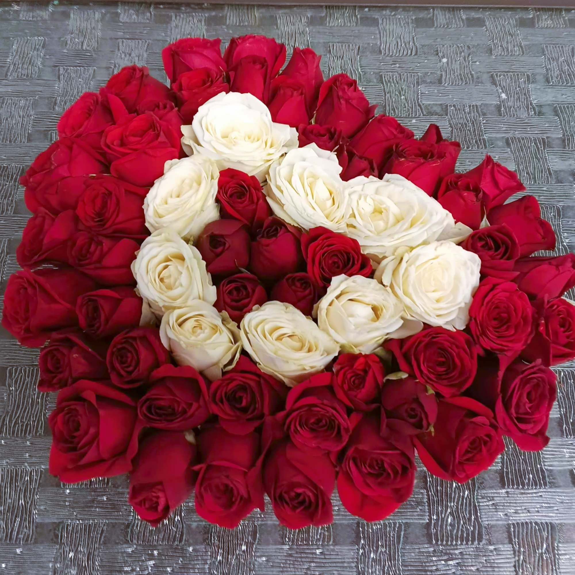 A large arrangement of red and white roses laid in a circular pattern.