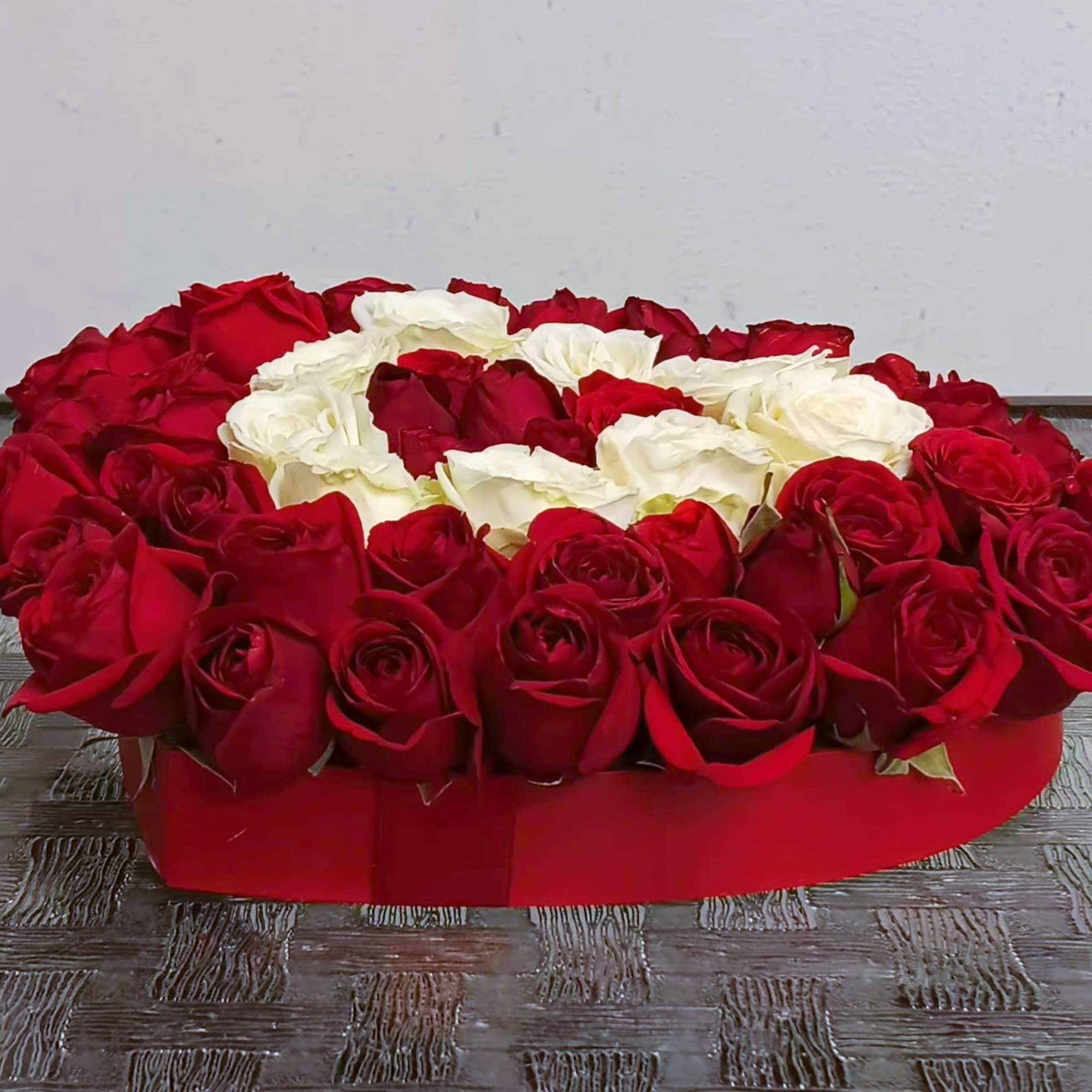 Heart-shaped arrangement of red and white roses in a red box