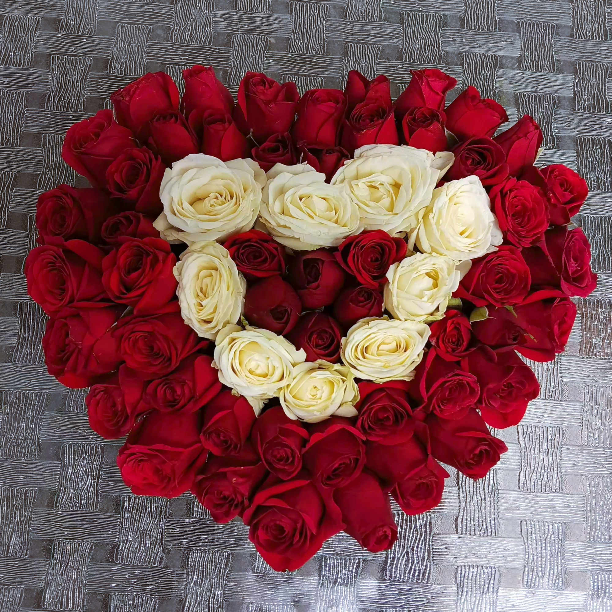 Heart-shaped arrangement of red and white roses