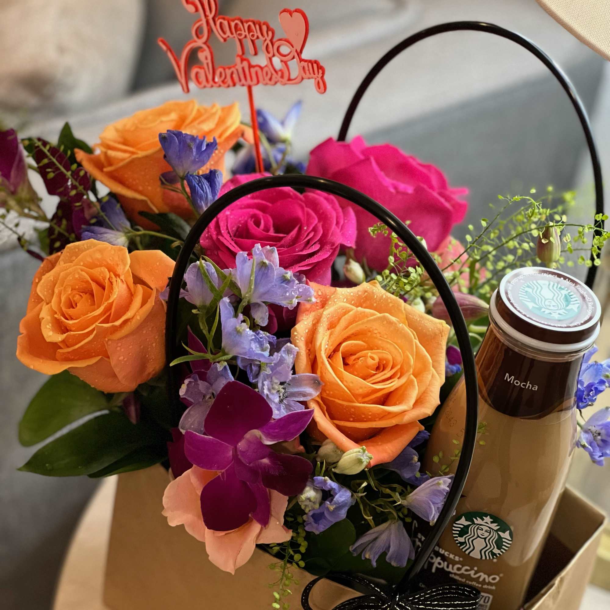 Bouquet of orange and pink roses with purple flowers in a gift box