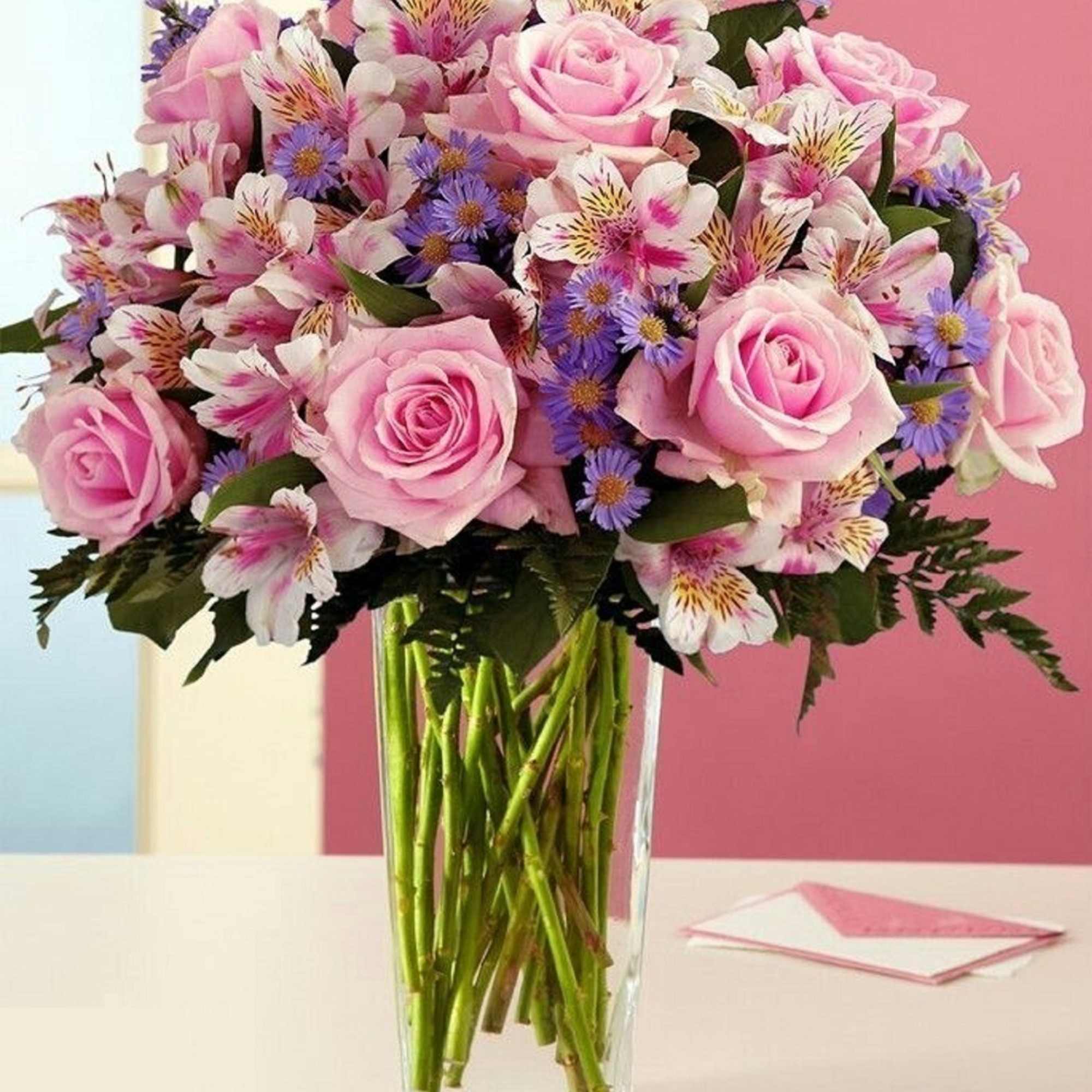 Pink roses and white alstroemeria in a clear glass vase
