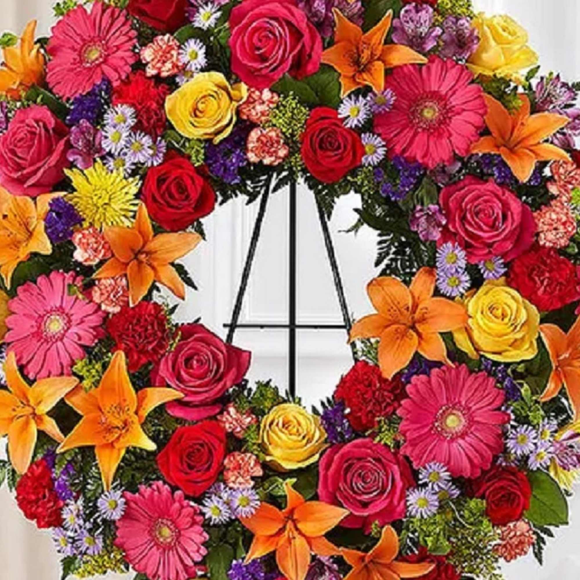 Colorful floral wreath with roses, lilies, and daisies on a stand