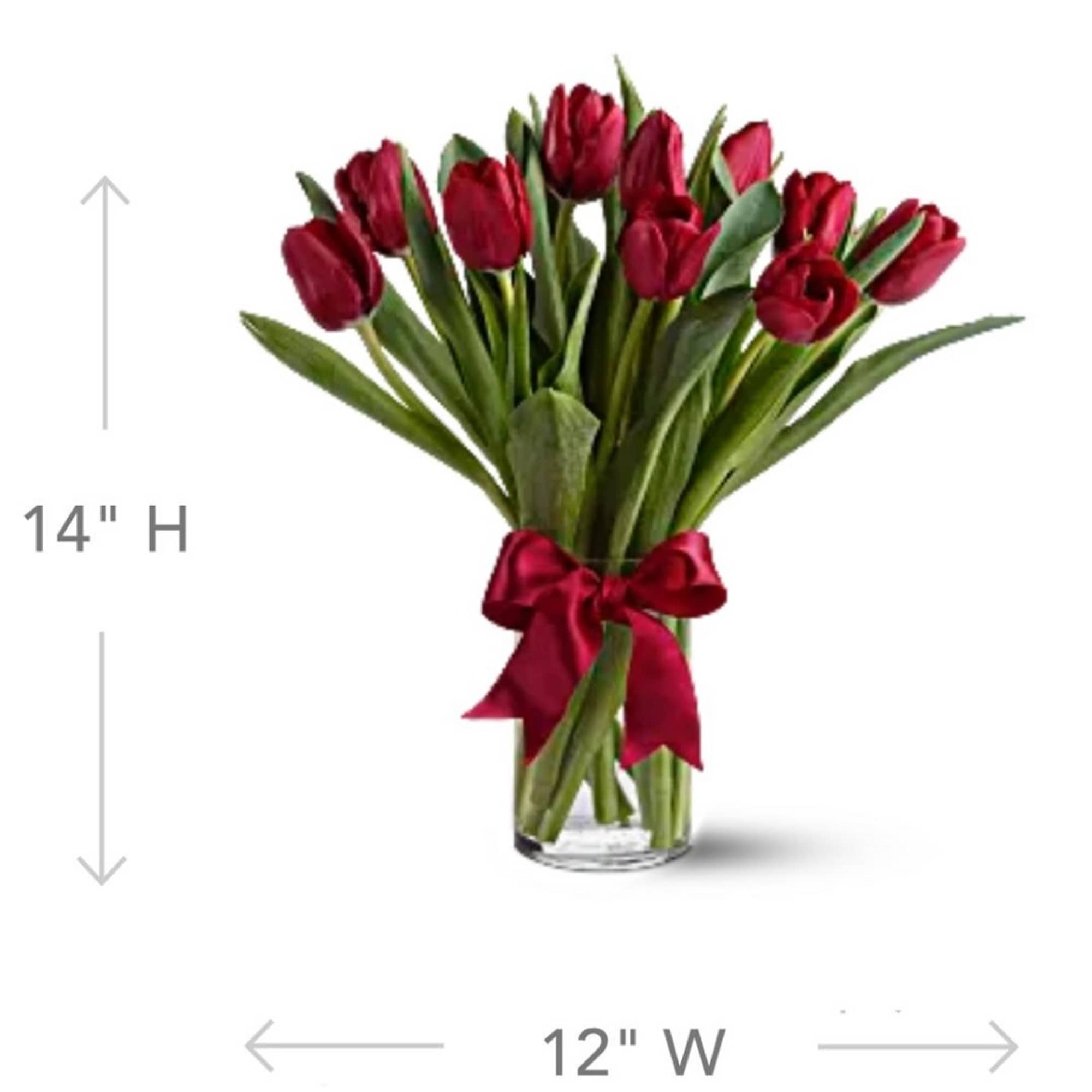 Red tulip bouquet in a clear glass vase with a satin ribbon