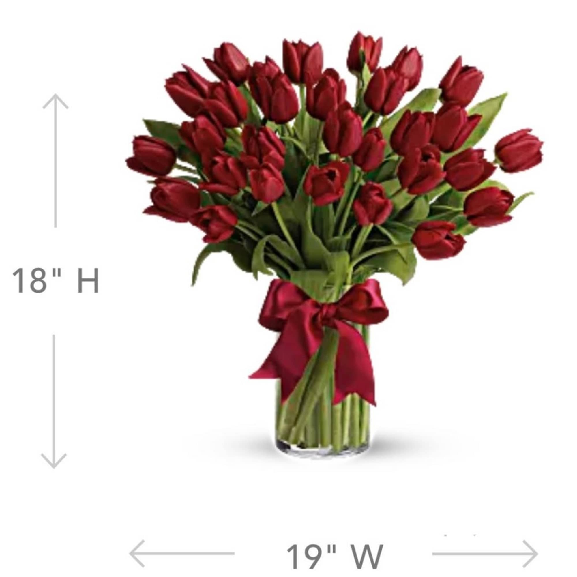 Bouquet of red tulips tied with a burgundy ribbon in a glass vase