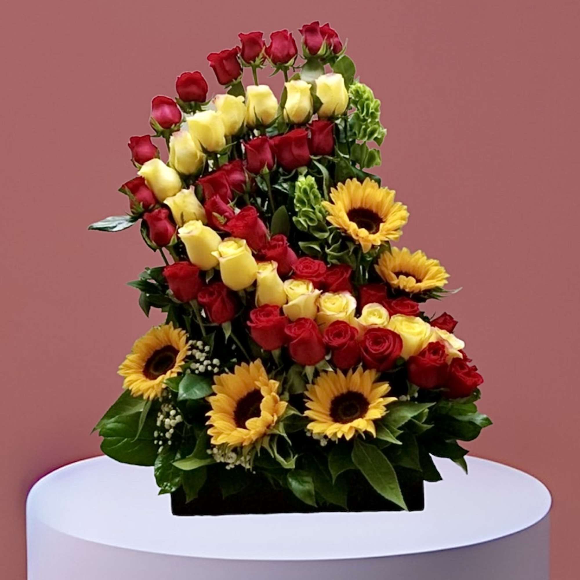 Tiered bouquet of red and yellow roses with sunflowers in a black container