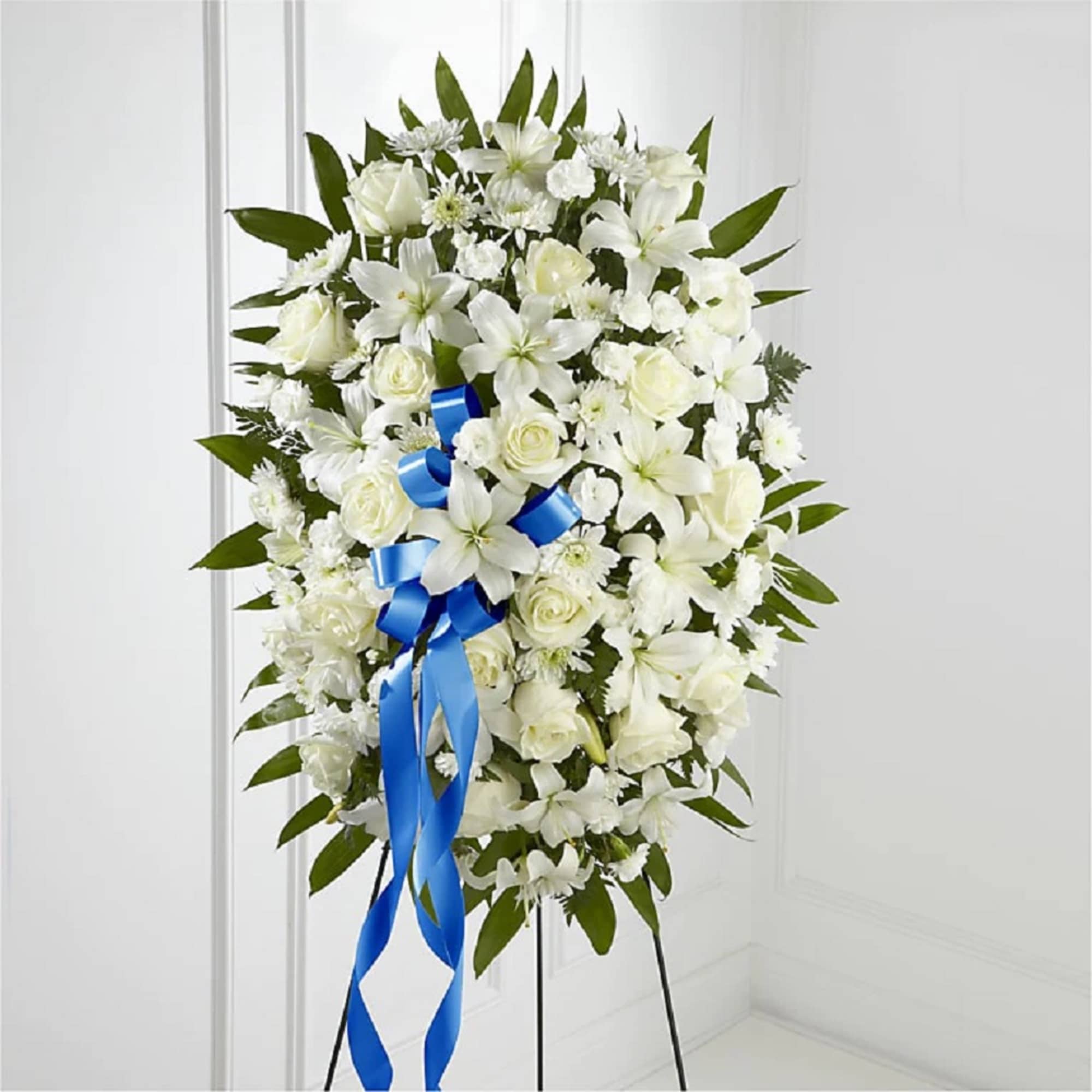 White floral standing spray with a blue ribbon on an easel
