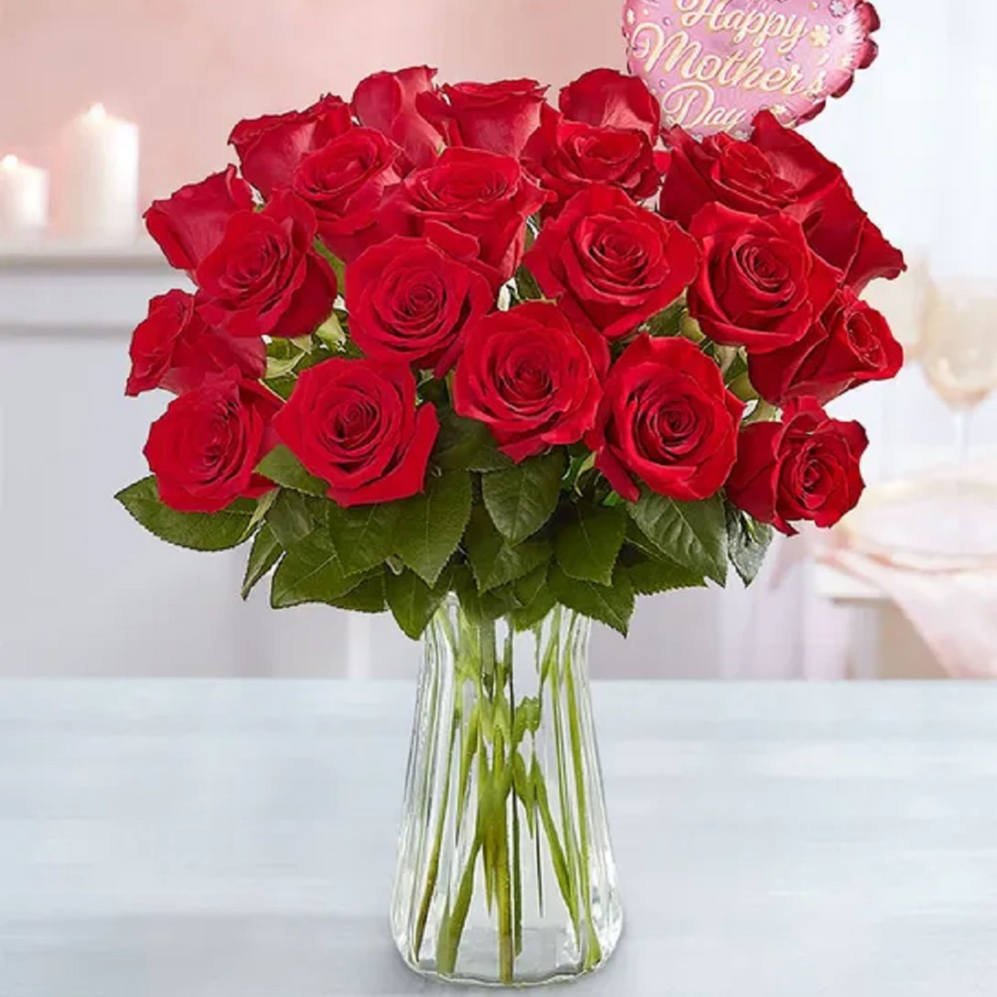 Red roses in a clear glass vase with a pink heart balloon