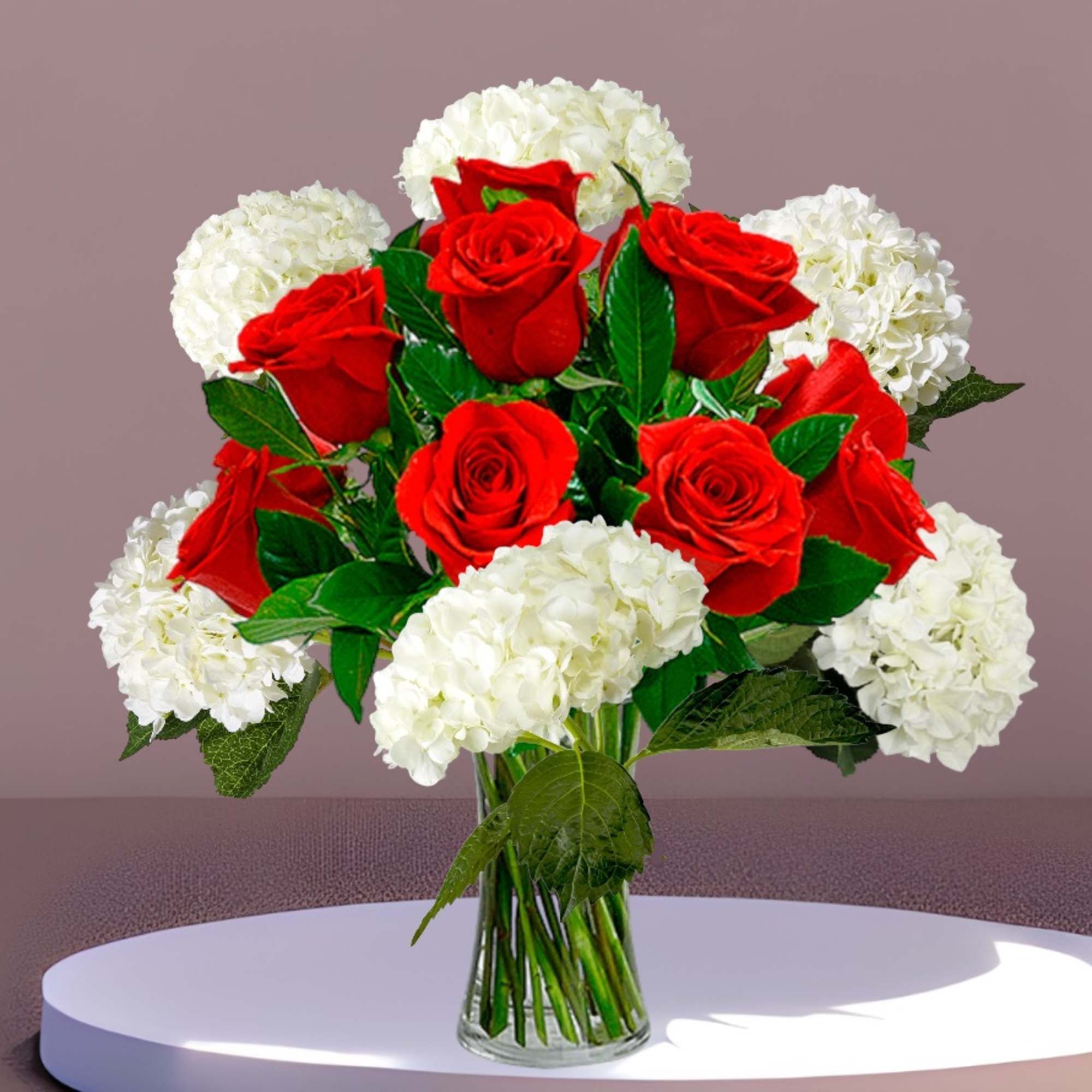Red roses and white hydrangeas arranged in a clear glass vase