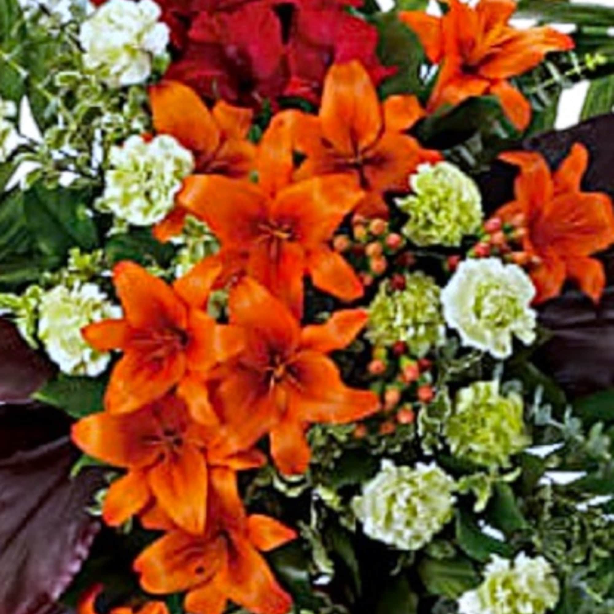 Orange and red lilies with white filler flowers and palm fronds