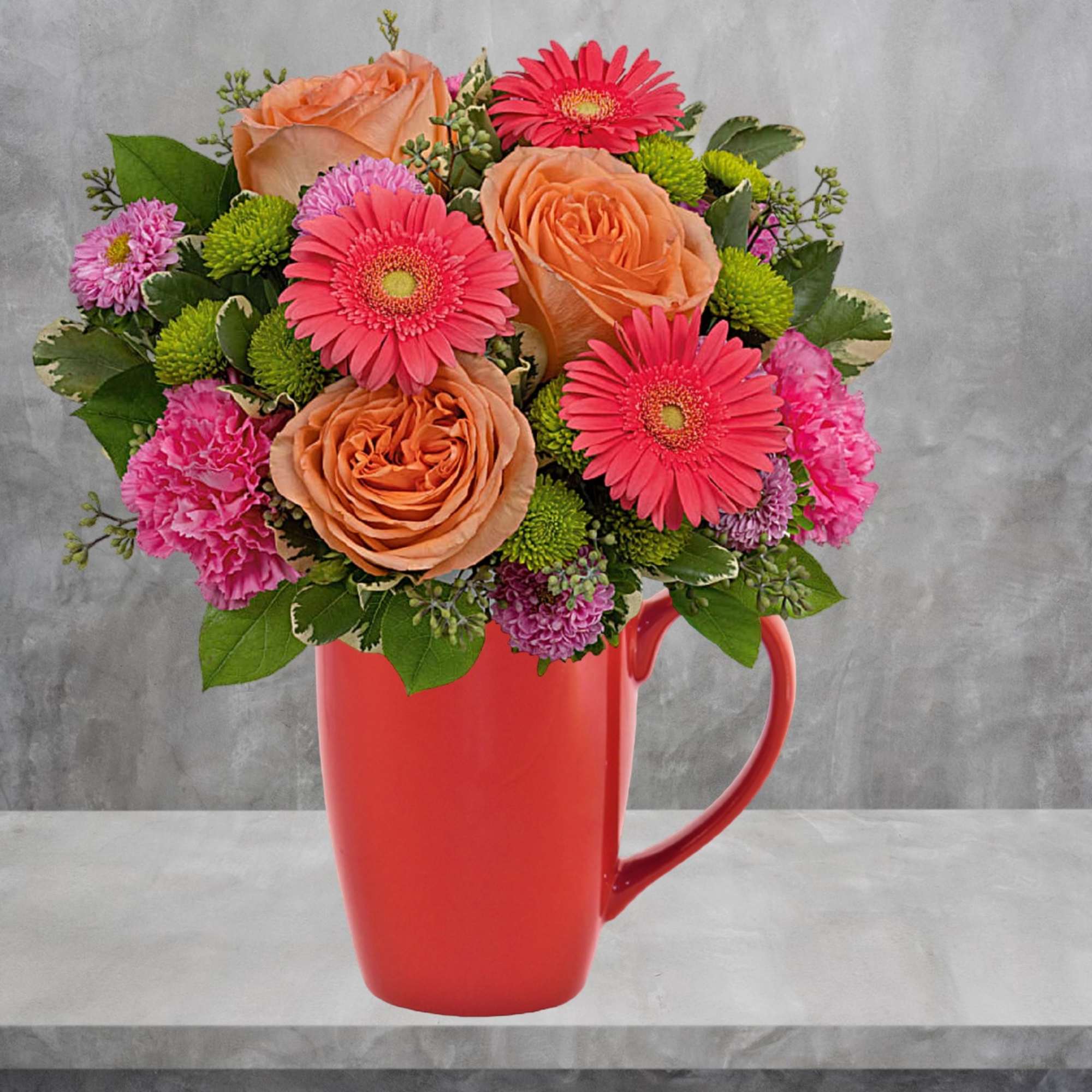 Bouquet of peach roses, pink gerbera daisies, and carnations in a red mug