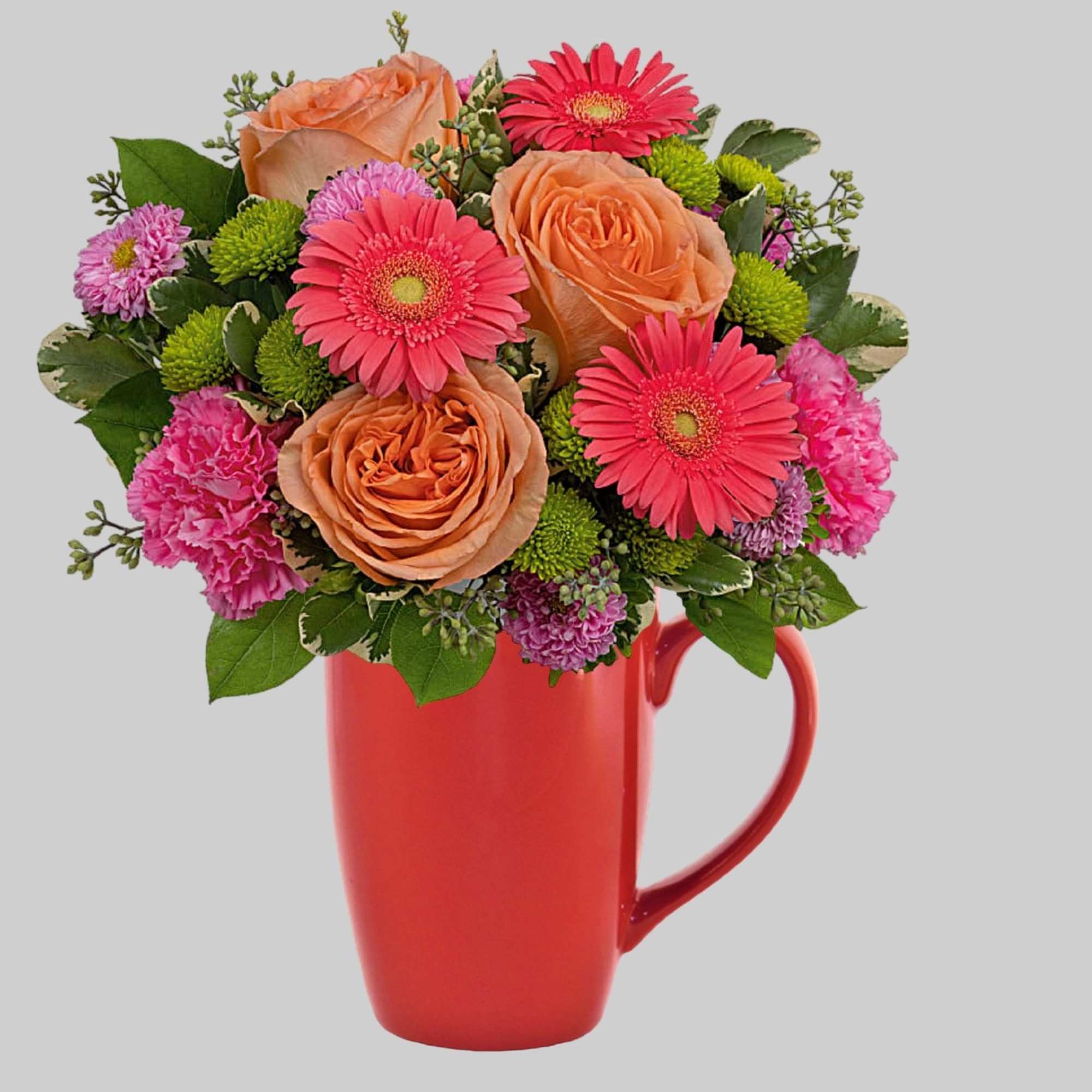 Pink and peach flowers arranged in a red mug vase