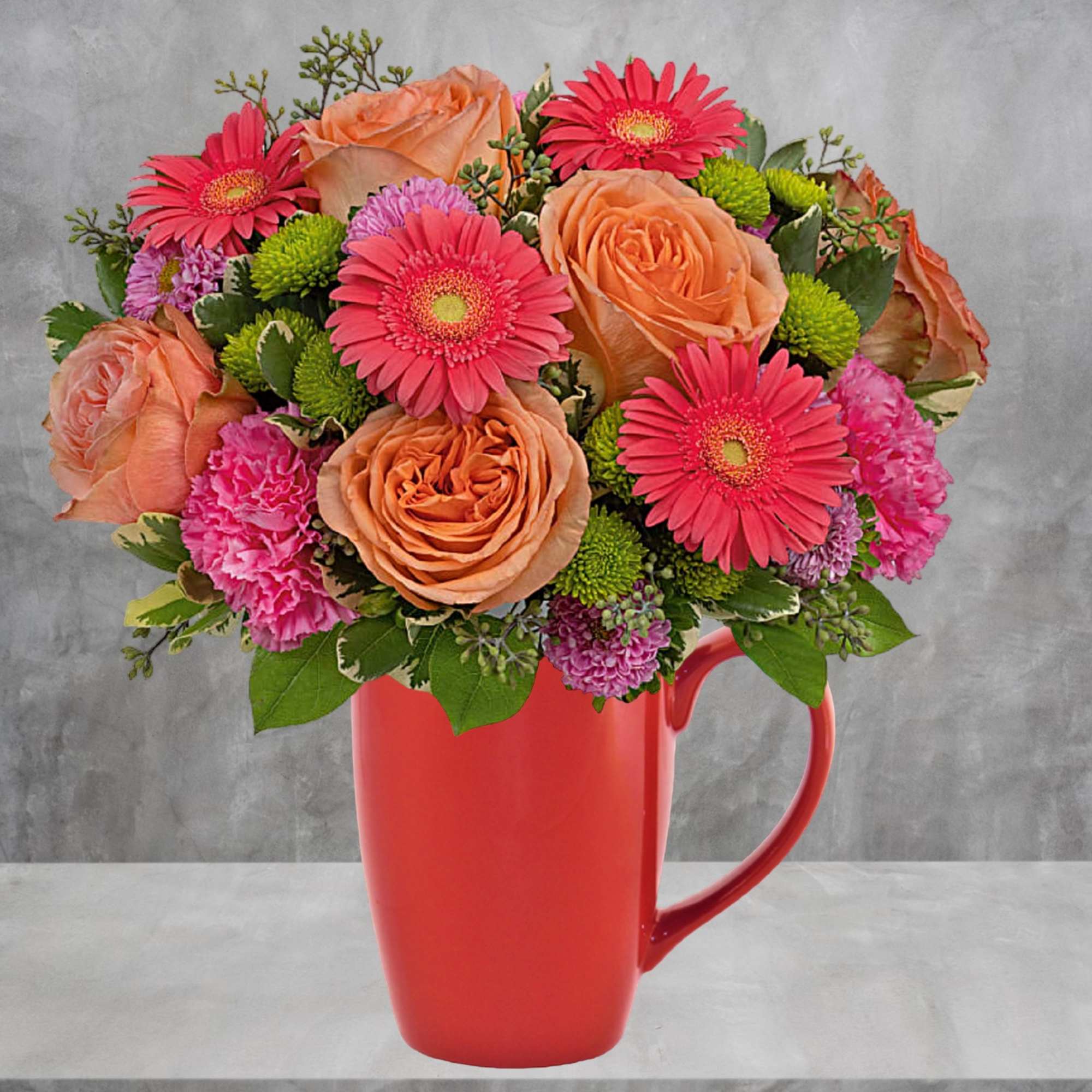Bouquet of peach roses, pink gerbera daisies, and carnations in a red mug vase